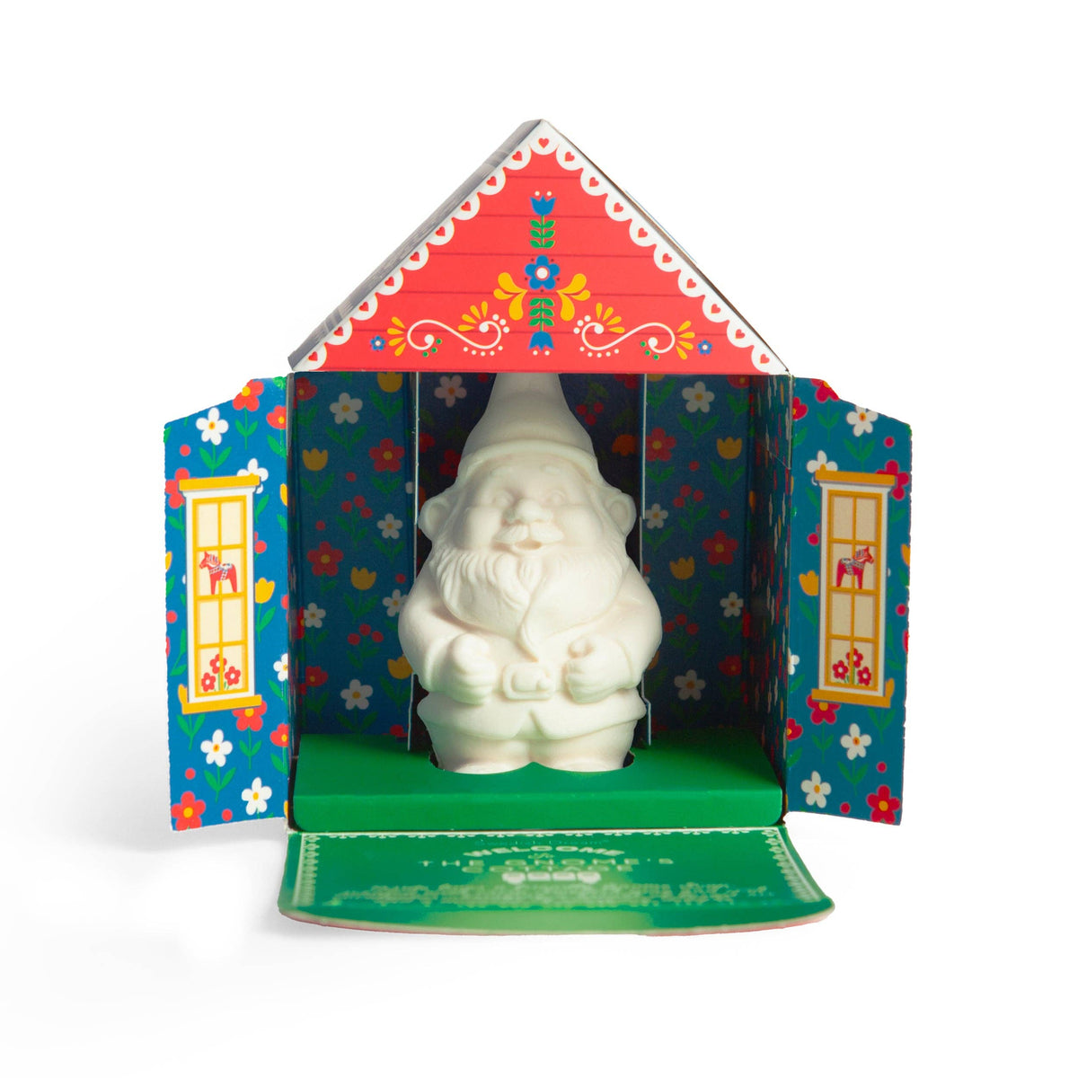 White chocolate gnome inside a colorful, house-shaped box with Nordic floral patterns and open doors.