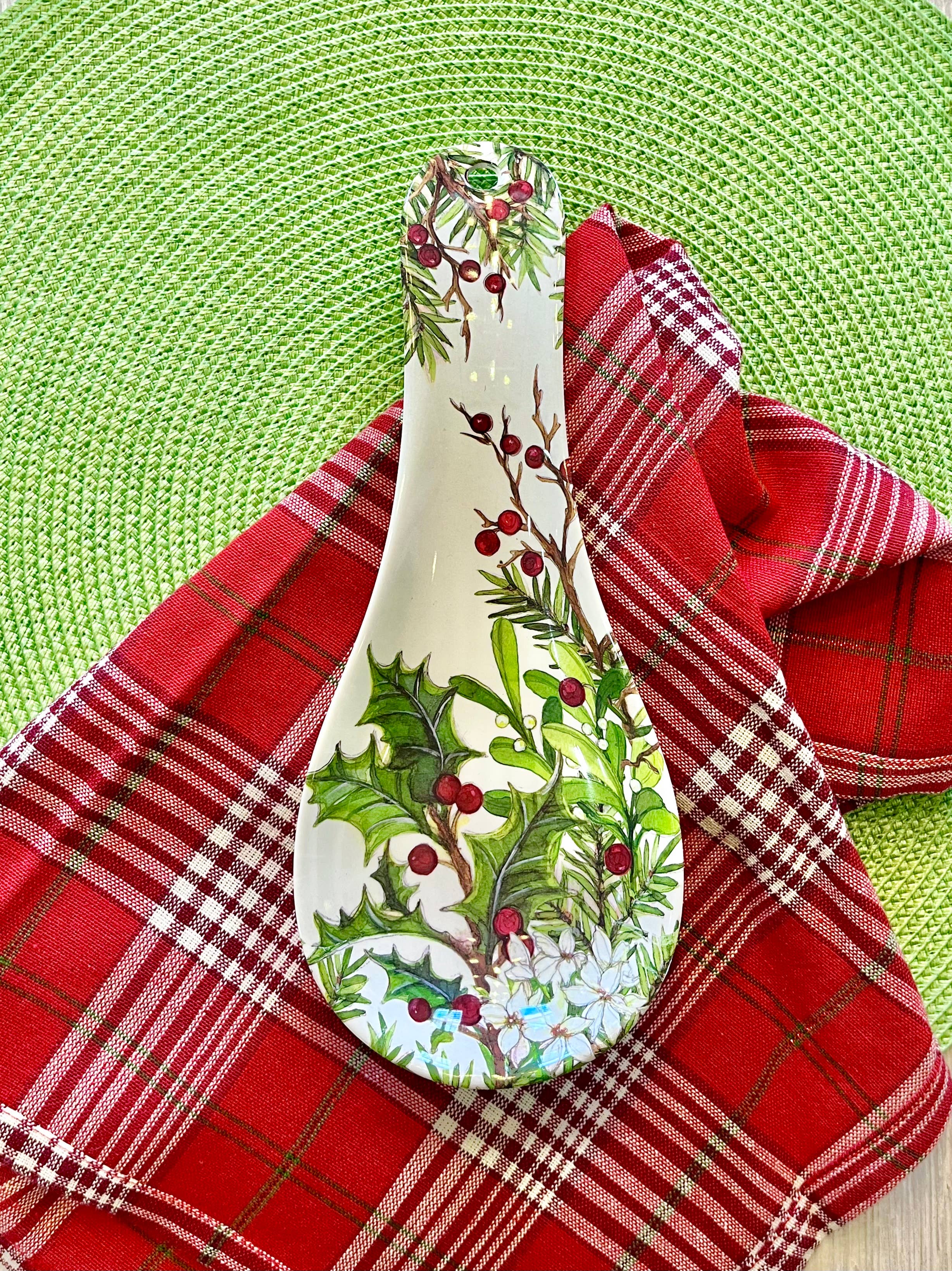 The Spoon Rest: Holly & Berries Christmas Holiday sits on a red plaid cloth over a green woven placemat, bringing festive cheer and seasonal style to your eco-friendly dinnerware collection.