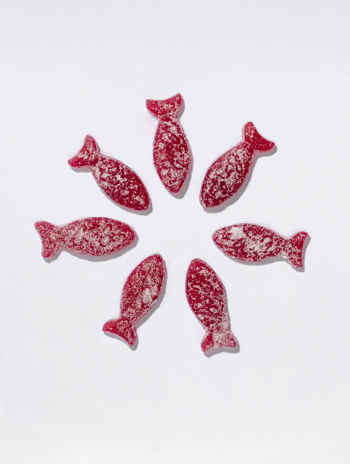 Seven Bon Bon - Sour Blackberry Fish candies (150g), a Swedish treat, are arranged in a circle on a white background and dusted with sugar.