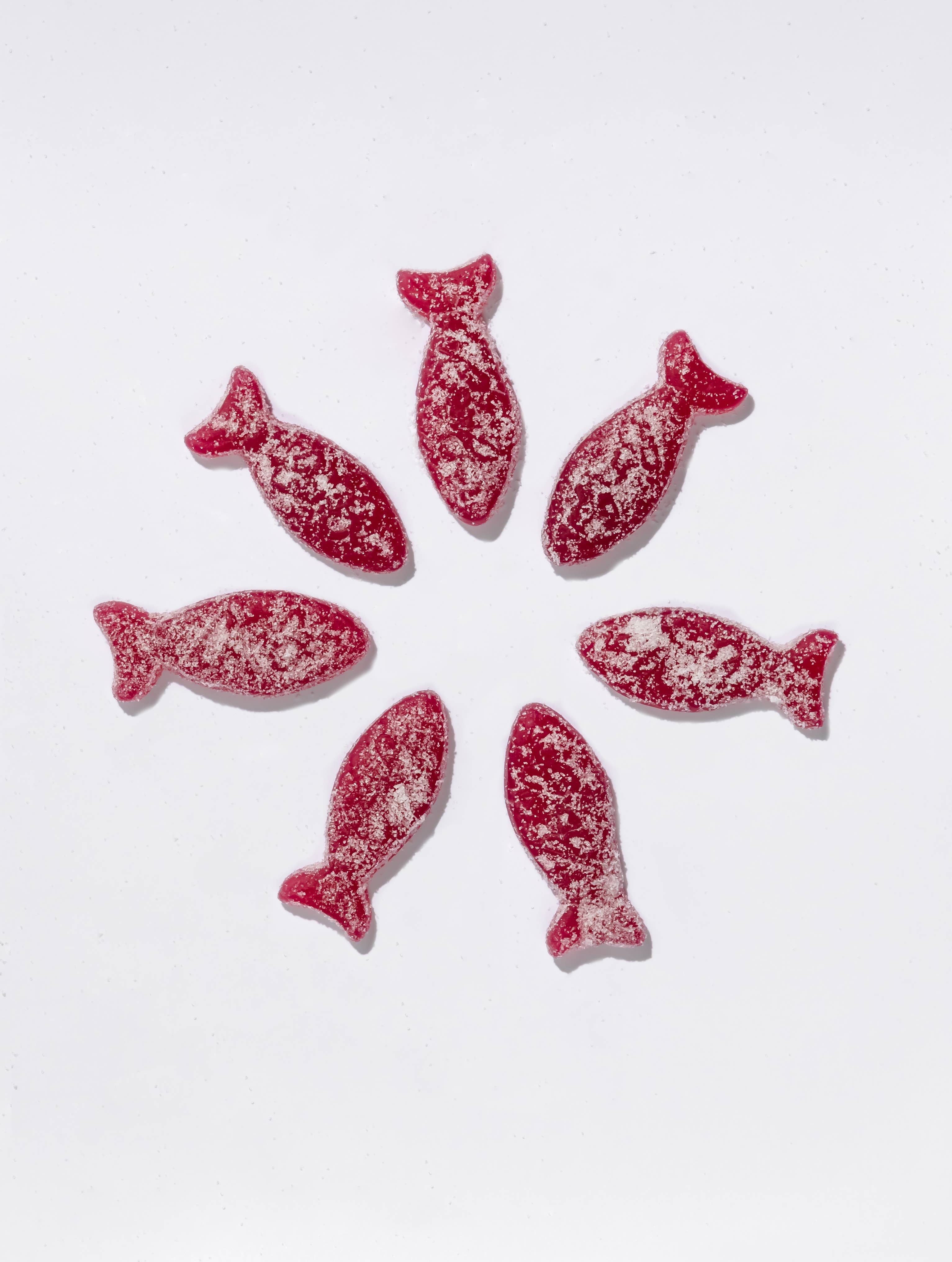 Seven Bon Bon - Sour Blackberry Fish candies (150g), a Swedish treat, are arranged in a circle on a white background and dusted with sugar.