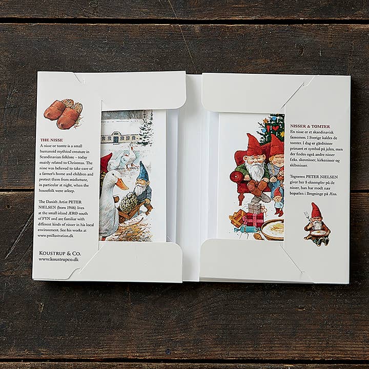 An open box displays the "Nisser" Christmas Gnomes card pack by Koustrupco, featuring 8 cards with Peter Nielsen's gnome and tomte art, each with a unique image, plus descriptions printed inside the cover. Includes 8 envelopes.