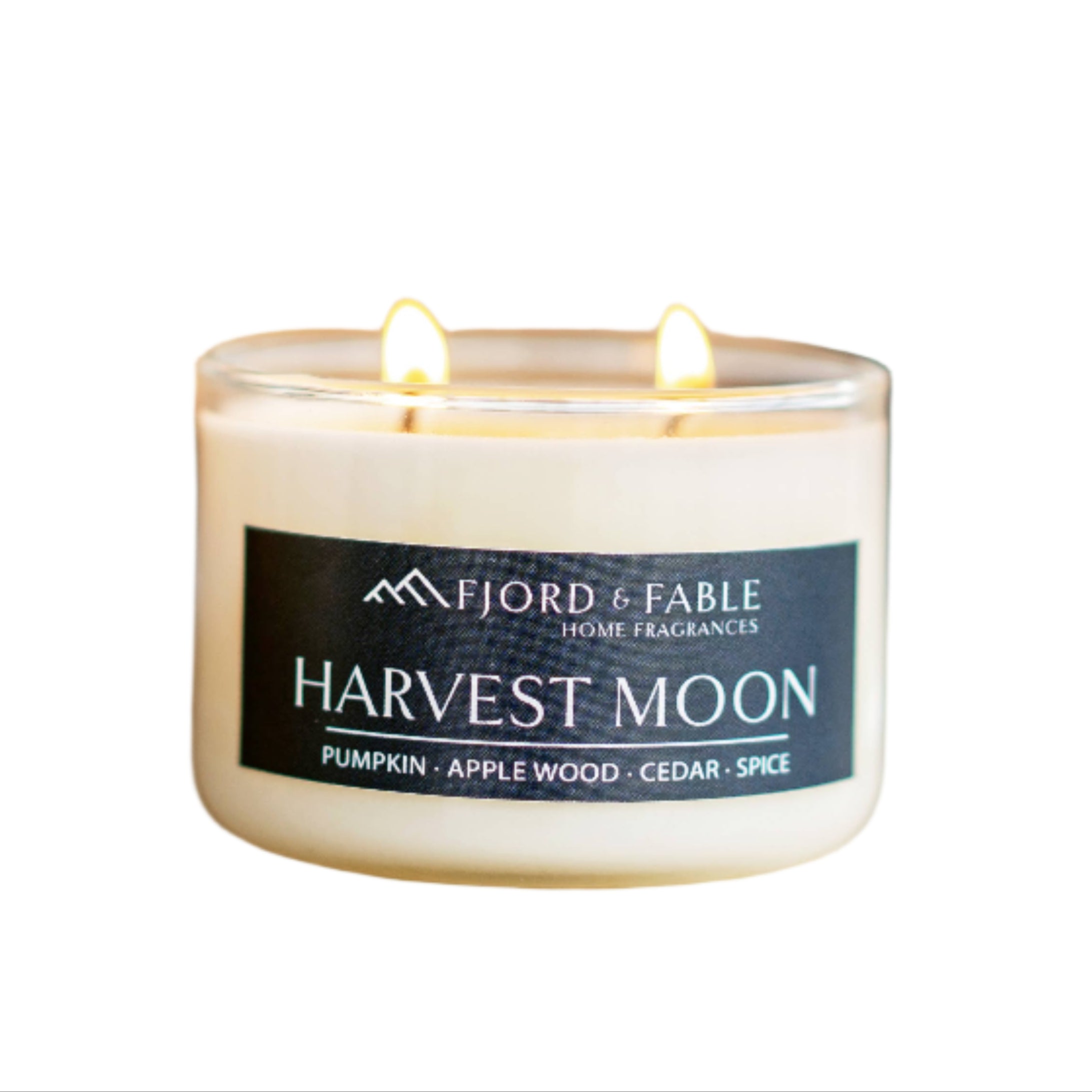Three white soy wax candles labeled Candle: Cedar Tobakk Candle (4oz, tobacco, amber, patchouli, peppercorn), with two lit, on a blurred background with warm light—featuring a rich scent of tobacco and amber.