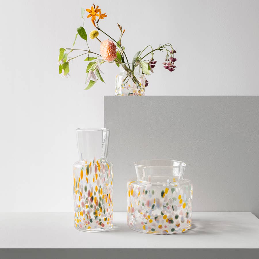 Three Meadow vases with multicolored confetti patterns, one holding a small bouquet of wildflowers.