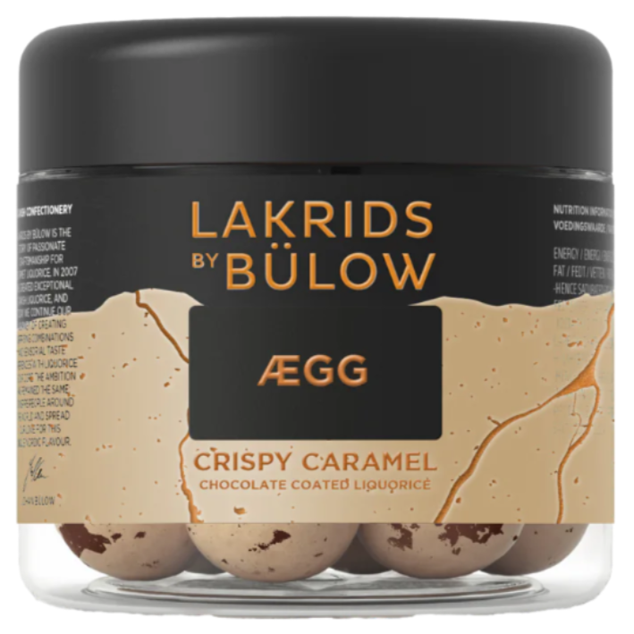 A 125g jar of Lakrids by Bulow Crispy Caramel features Danish chocolate-coated licorice with a crunchy core, presented in a clear container with a stylish black and gold label.