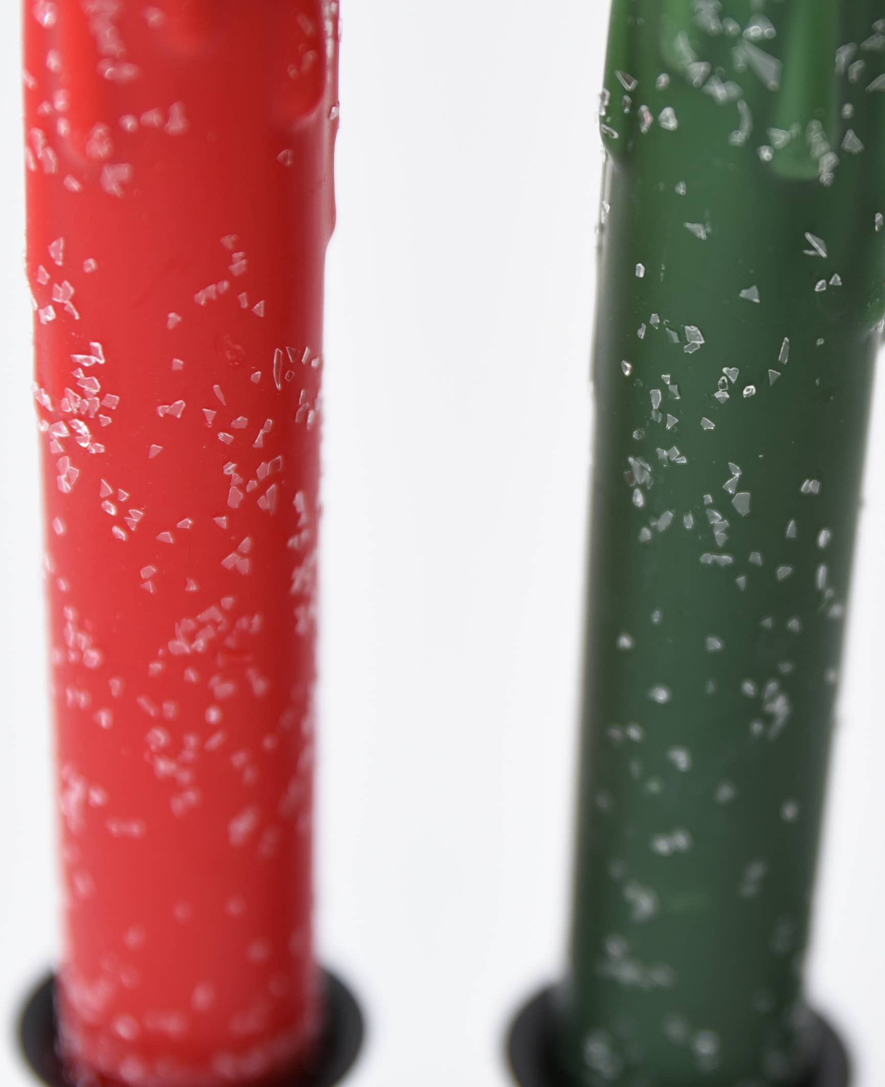 Close-up of Diamond Dusted Christmas LED Timer Taper Candles in red and green, featuring coarse salt crystals on their surfaces.
