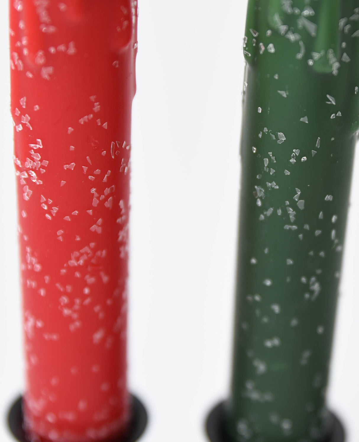 Close-up of Diamond Dusted Christmas LED Timer Taper Candles in red and green, featuring coarse salt crystals on their surfaces.