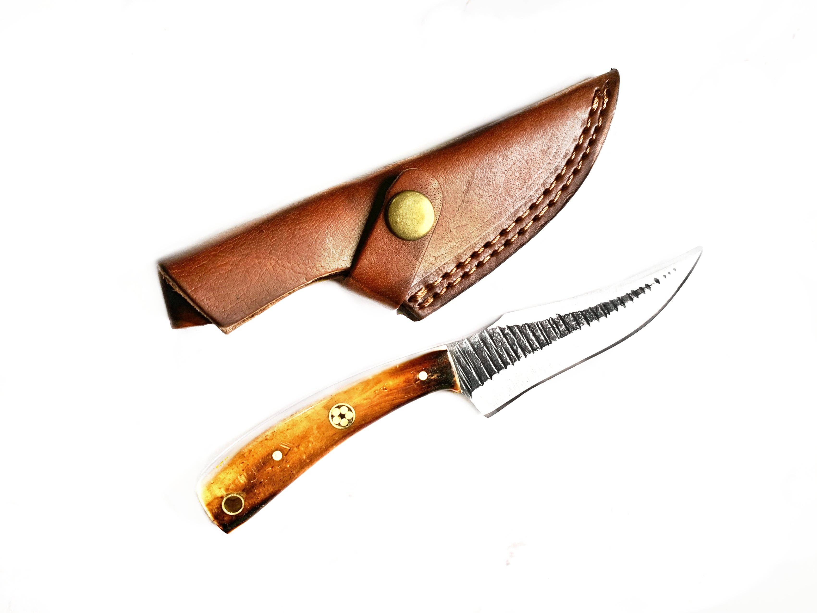 The Knife: Carbon Skinning/ Hunting Knife, featuring a high carbon steel fixed blade and a wooden handle, is shown below a brown leather sheath on a white background.