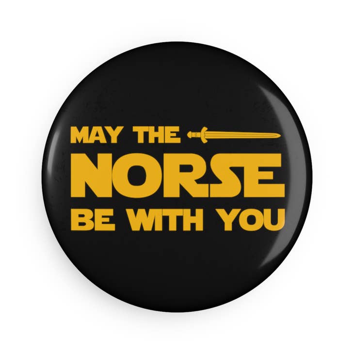 Round black magnet featuring yellow text that reads "May the Norse Be With You" and includes a sword graphic.