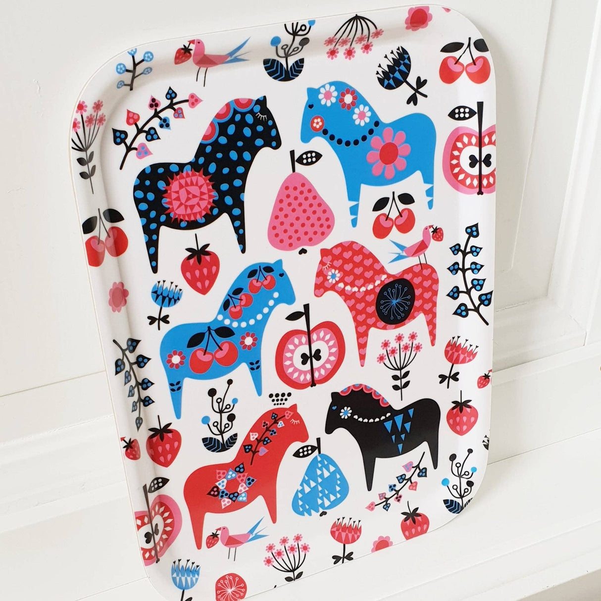 The Swedish Dala Horse Birch-Wood Tray (approx. 8x10.5 inches) is made in Sweden and features blue, red, and pink horse illustrations with flowers and berries on a white background.