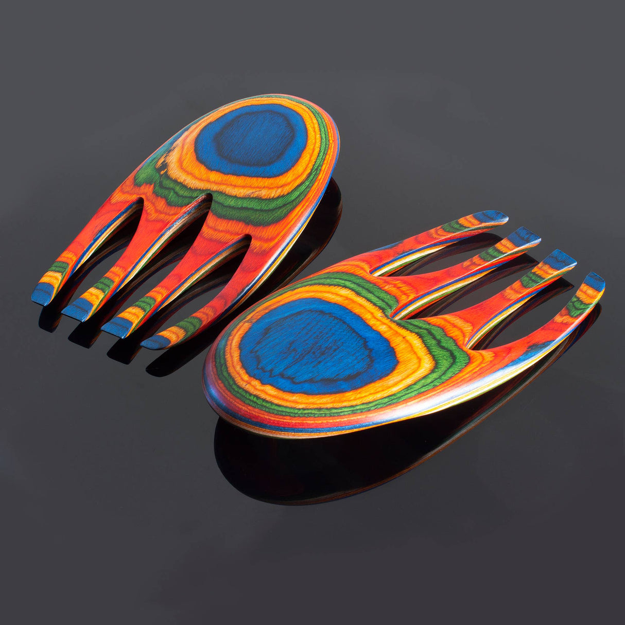 Two Utensil: Colorful Birch Salad Hands, Salad Serving Utensils with a vibrant, layered rainbow pattern rest on a reflective black surface.