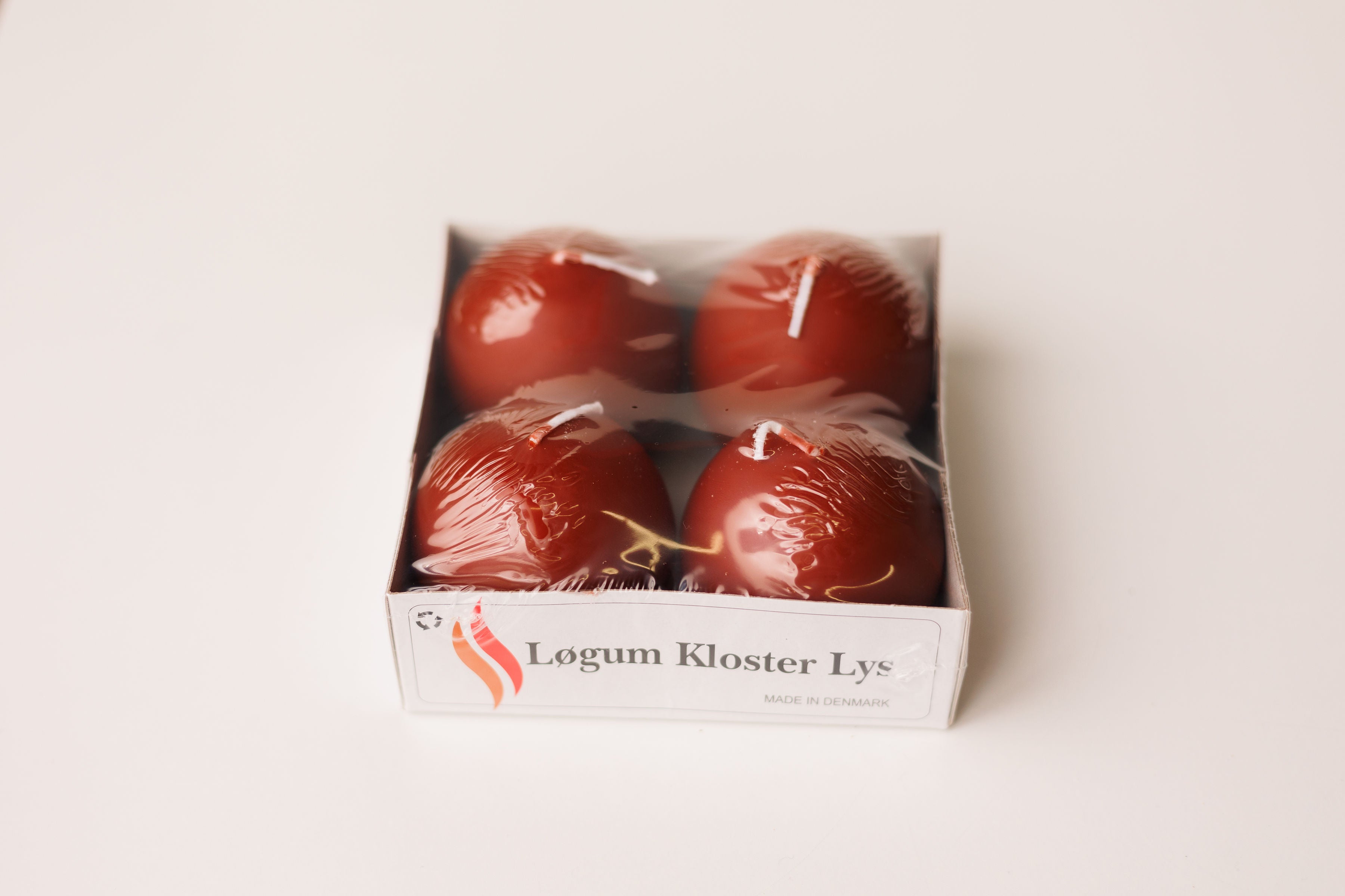 A 4-pack of Logum Kloster Lys 2.5 red ball candles from Denmark, wrapped in plastic, displayed on a white background.