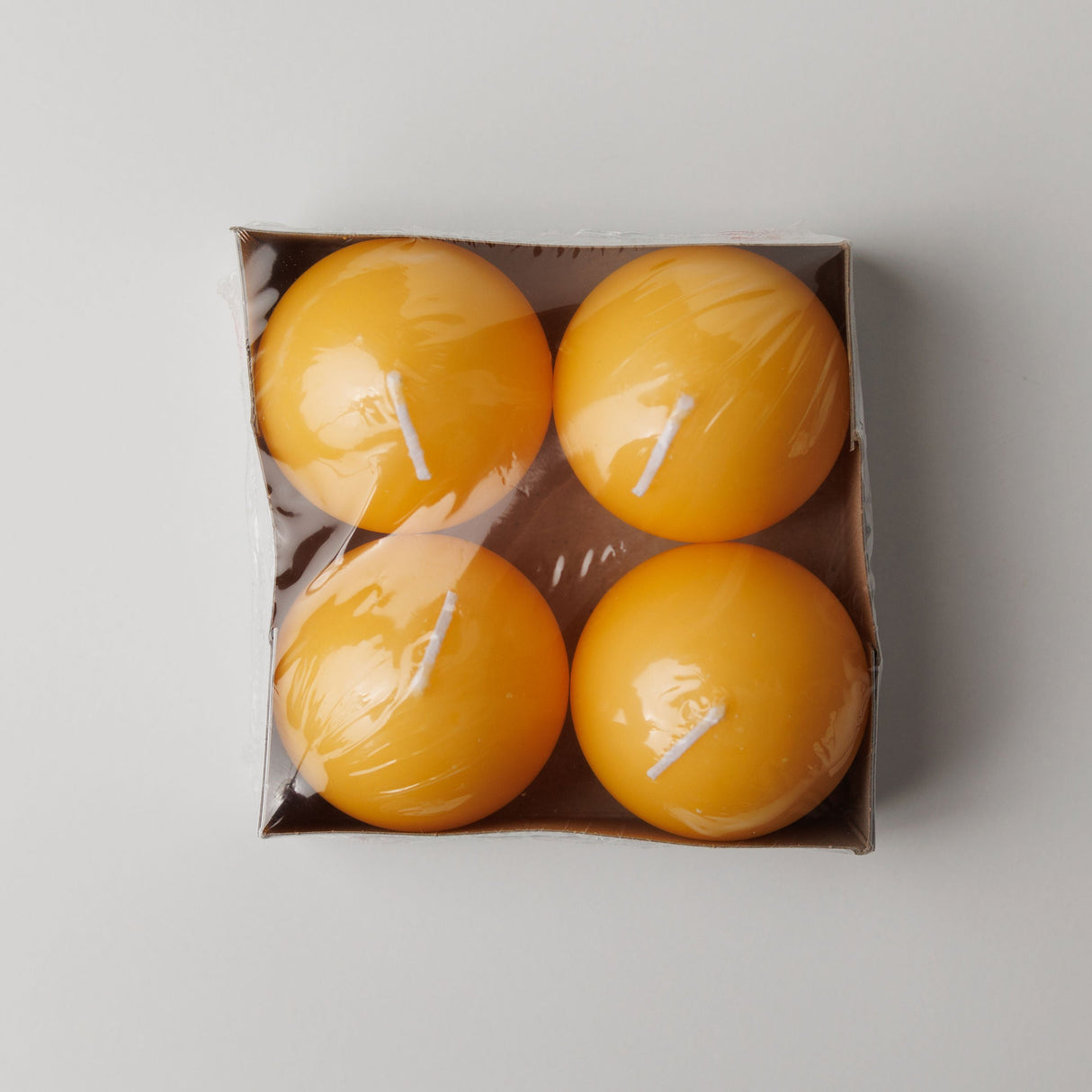 A cardboard box of Logum Kloster Lys 2.5 yellow ball candles (4 pack), wrapped in clear plastic, viewed from above against a light background.