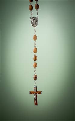 The Rosary: Olive Wood Rosary with Crucifix from the Holy Land Made in Bethlehem – Israel hangs against a plain, light green background, showcasing its brown beads, medallion, and metal crucifix.