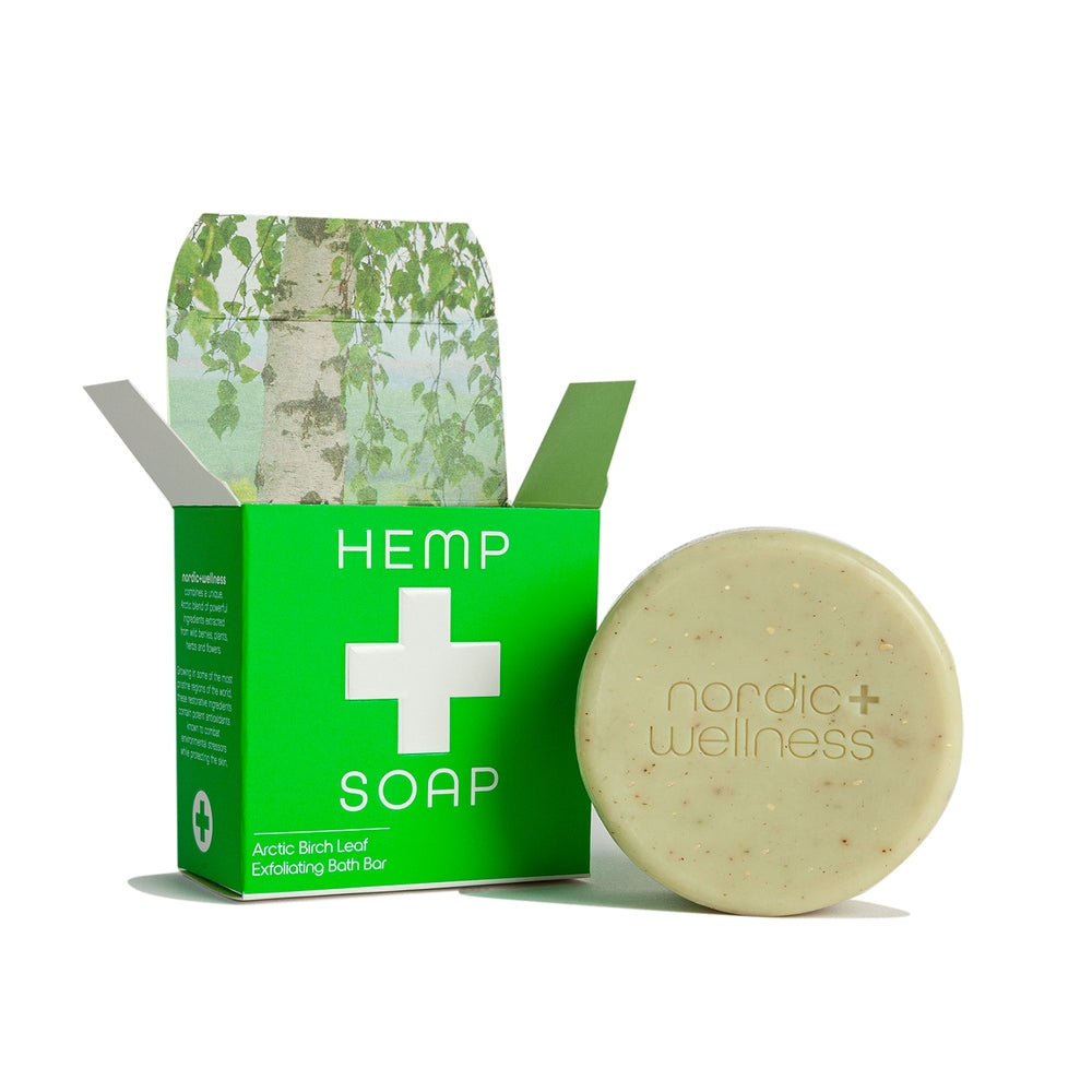 The Nordic + Wellness Birch Leaf Exfoliating Bath Bar Soap rests next to a green “HEMP SOAP” box with birch leaf imagery, capturing the fresh, pure spirit of Nordic wellness.