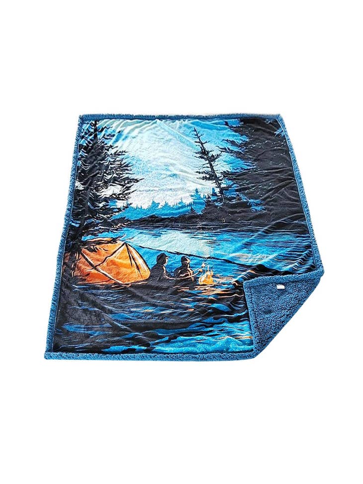 The S'mores Fleece Blanket is incredibly soft and features an illustration of a tent, two people by a campfire, and a forest backdrop under a starry night sky. Additionally, it is machine washable for easy care.