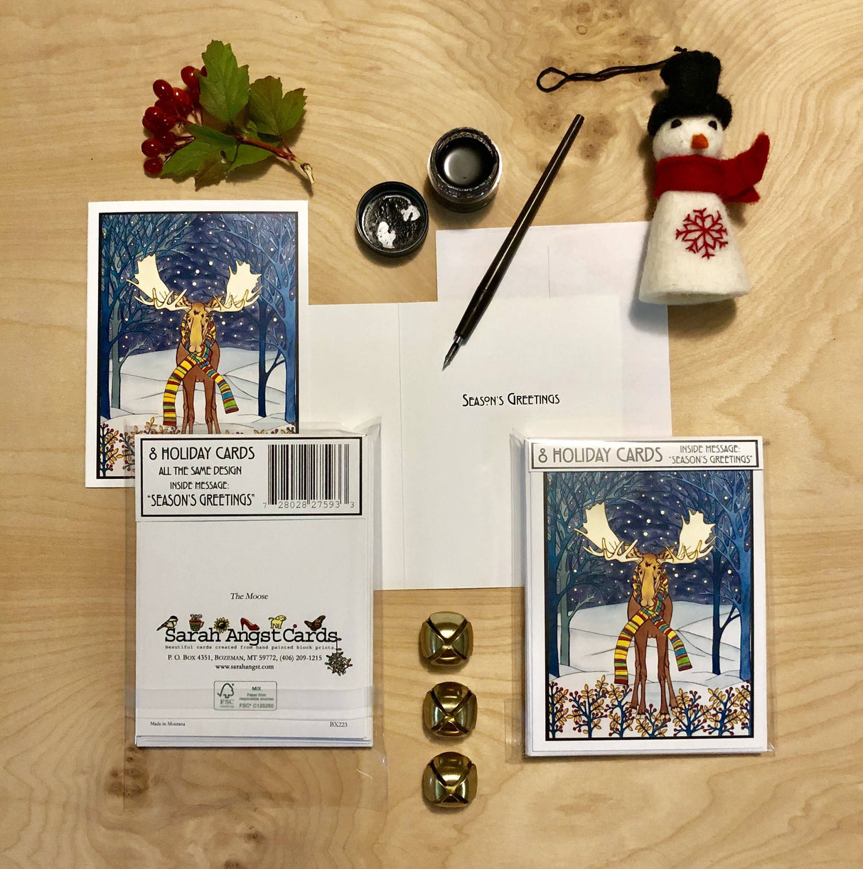 Card Pack: Holiday Moose Packaged Christmas Cards—8 cards with envelopes. Features a moose in snowy woods, bells, berries, and a felt snowman ornament. Envelope says Seasons Greetings. Made in USA for festive celebrations.