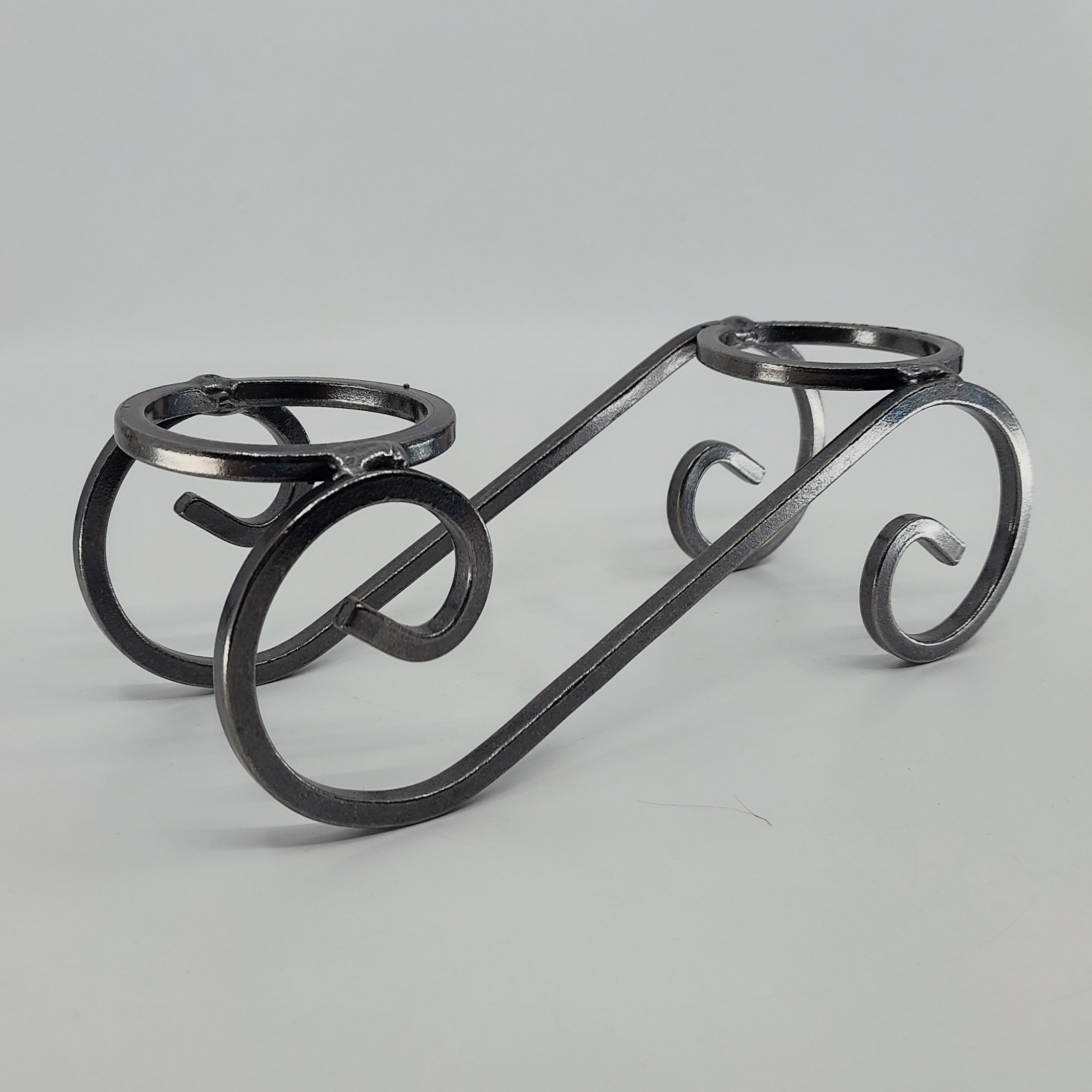 This Danish Iron Candleholder features two Leif glass cups for ball candles, showcasing black metal craftsmanship with a swirled design against a plain white backdrop.
