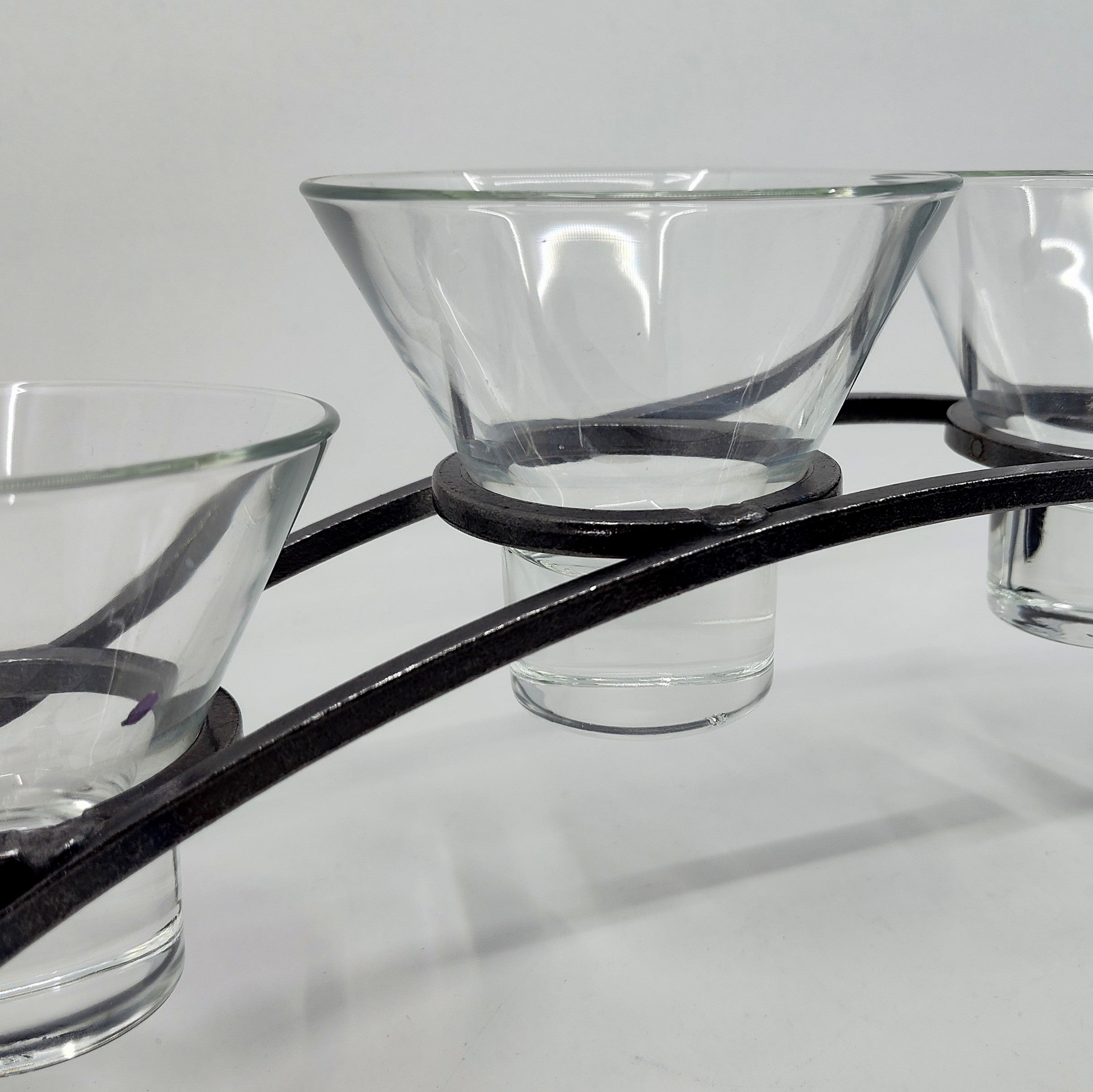 The Danish Iron Arched Candle Holder, featuring four Leif cups, elegantly displays glass candle holders against a plain background.