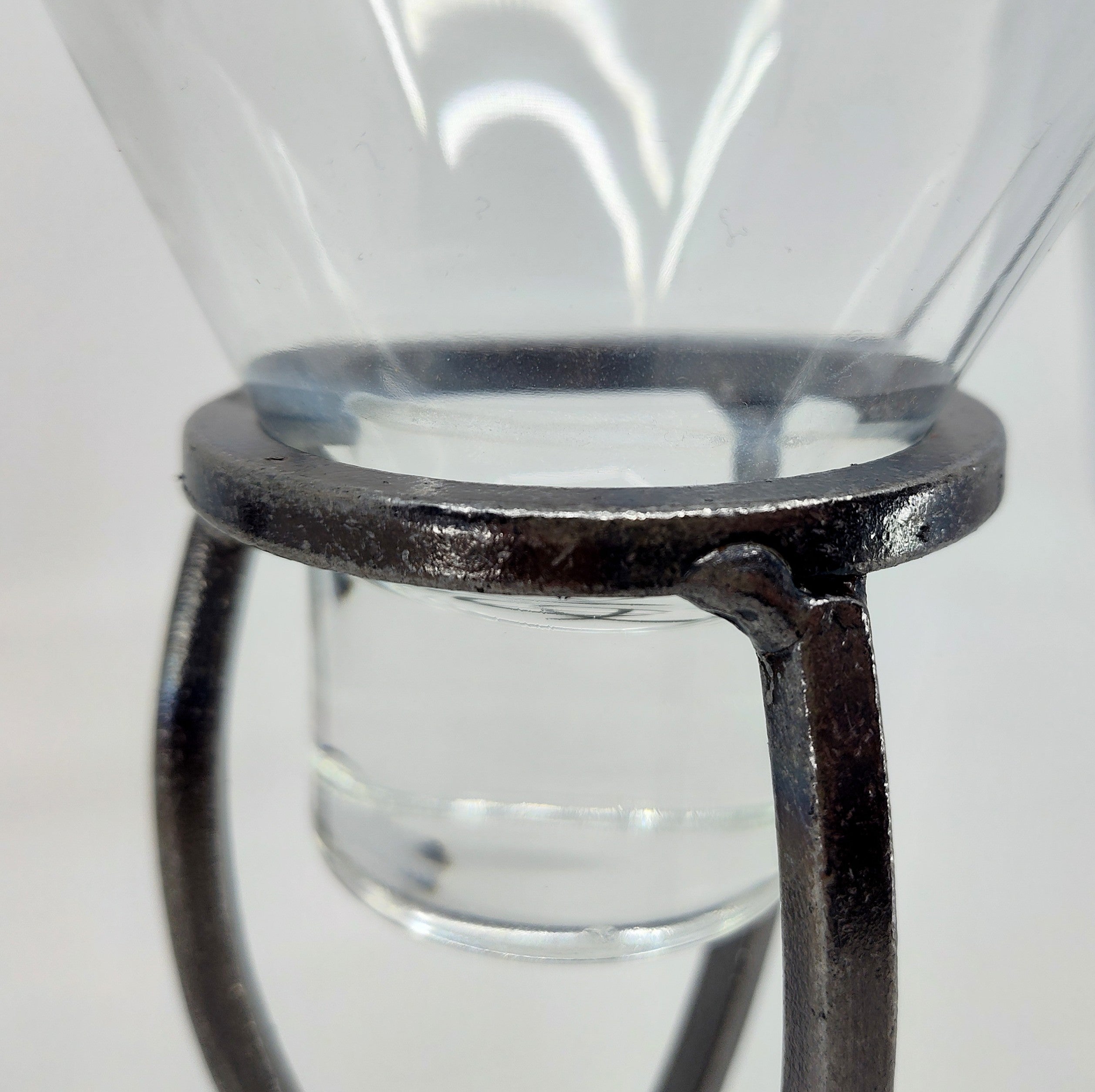 Close-up of a transparent glass funnel on a Danish Iron Candle Holder with Crossed Iron Base and Leif Cup for Ball Candle, against a plain white background.