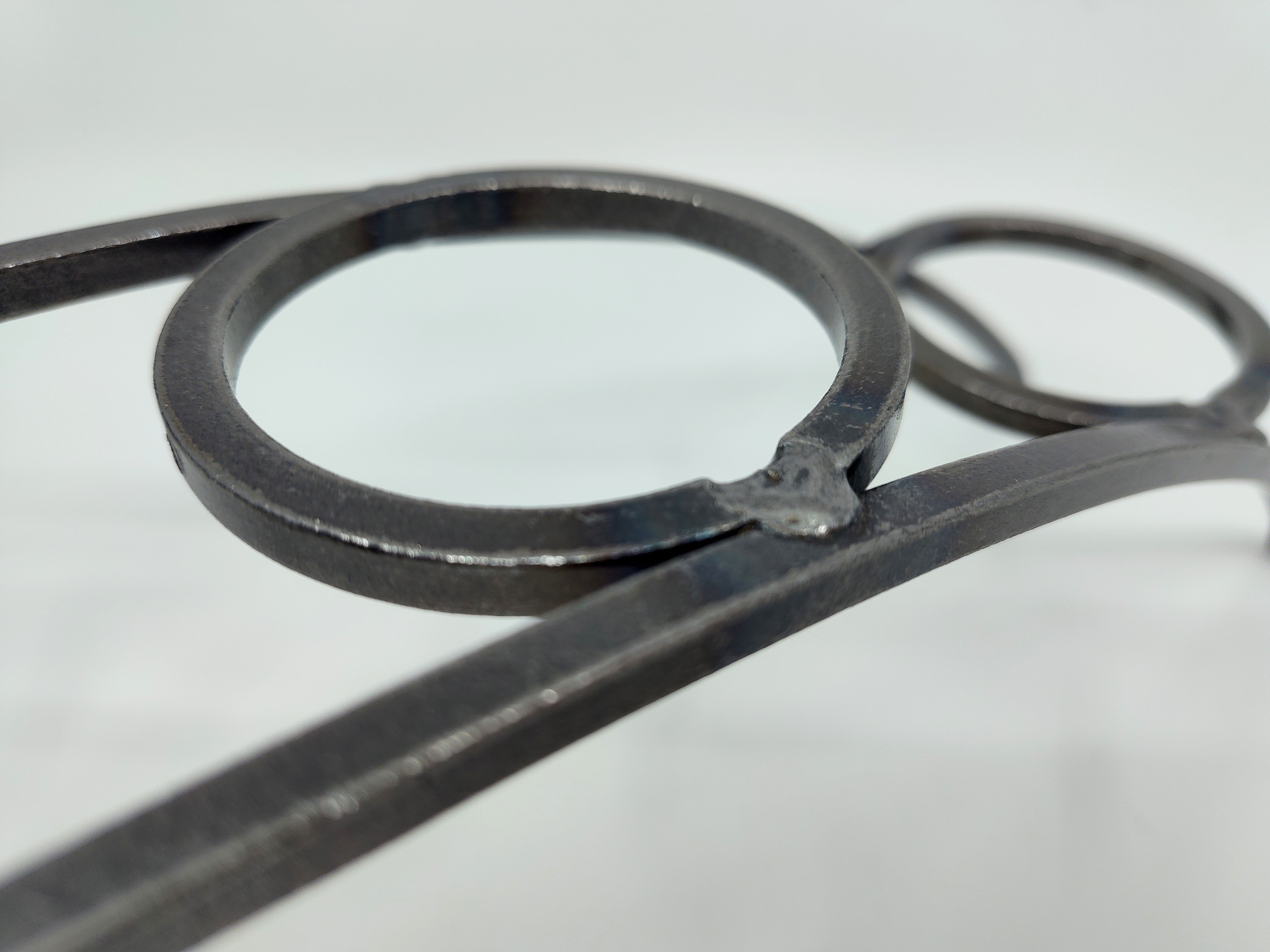 Close-up of the Danish Iron Arched Candle Holder featuring intersecting rings and curved bars with a beautifully crafted welded joint, plus 4 Leif cups for ball candles.