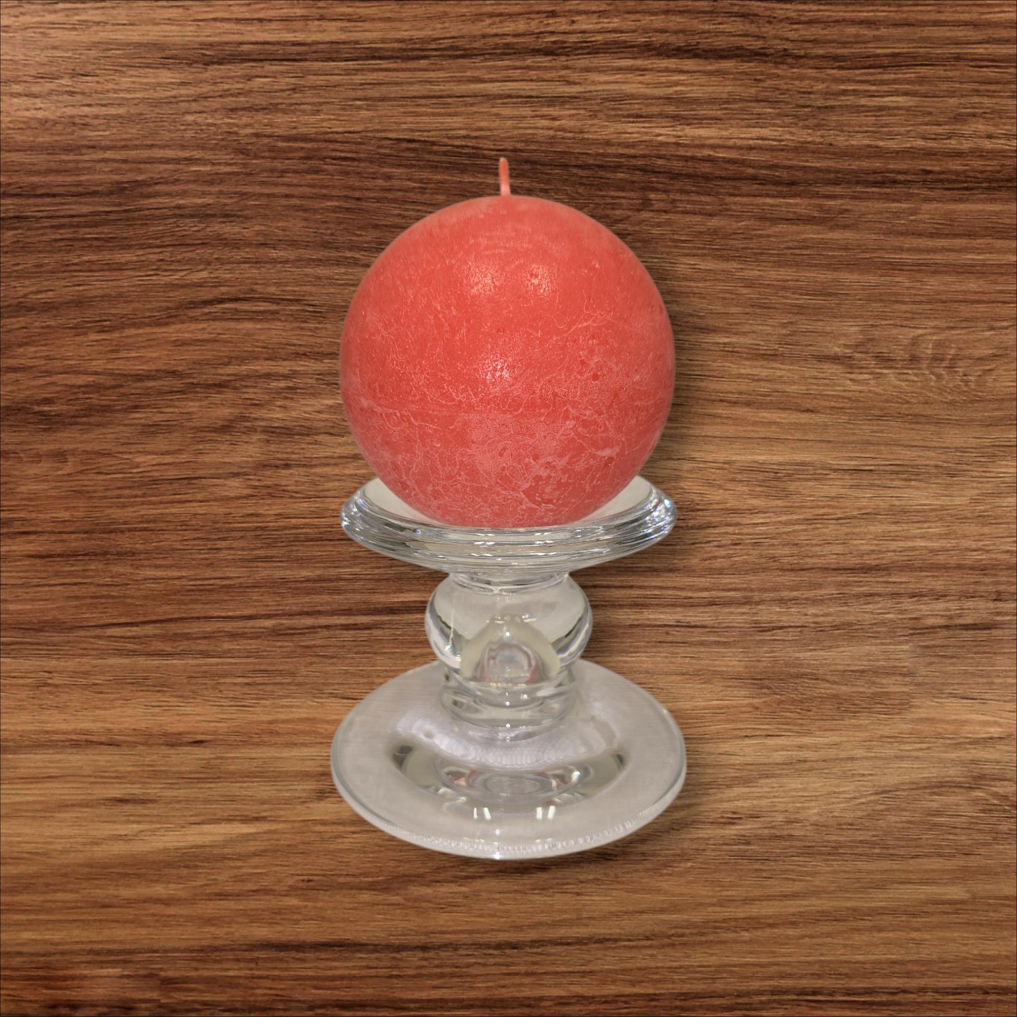 A round red candle rests on the Glass Dual-Size Reversible Candle Holder, designed for taper, ball, or pillar candles, displayed on a wood surface with visible grain.