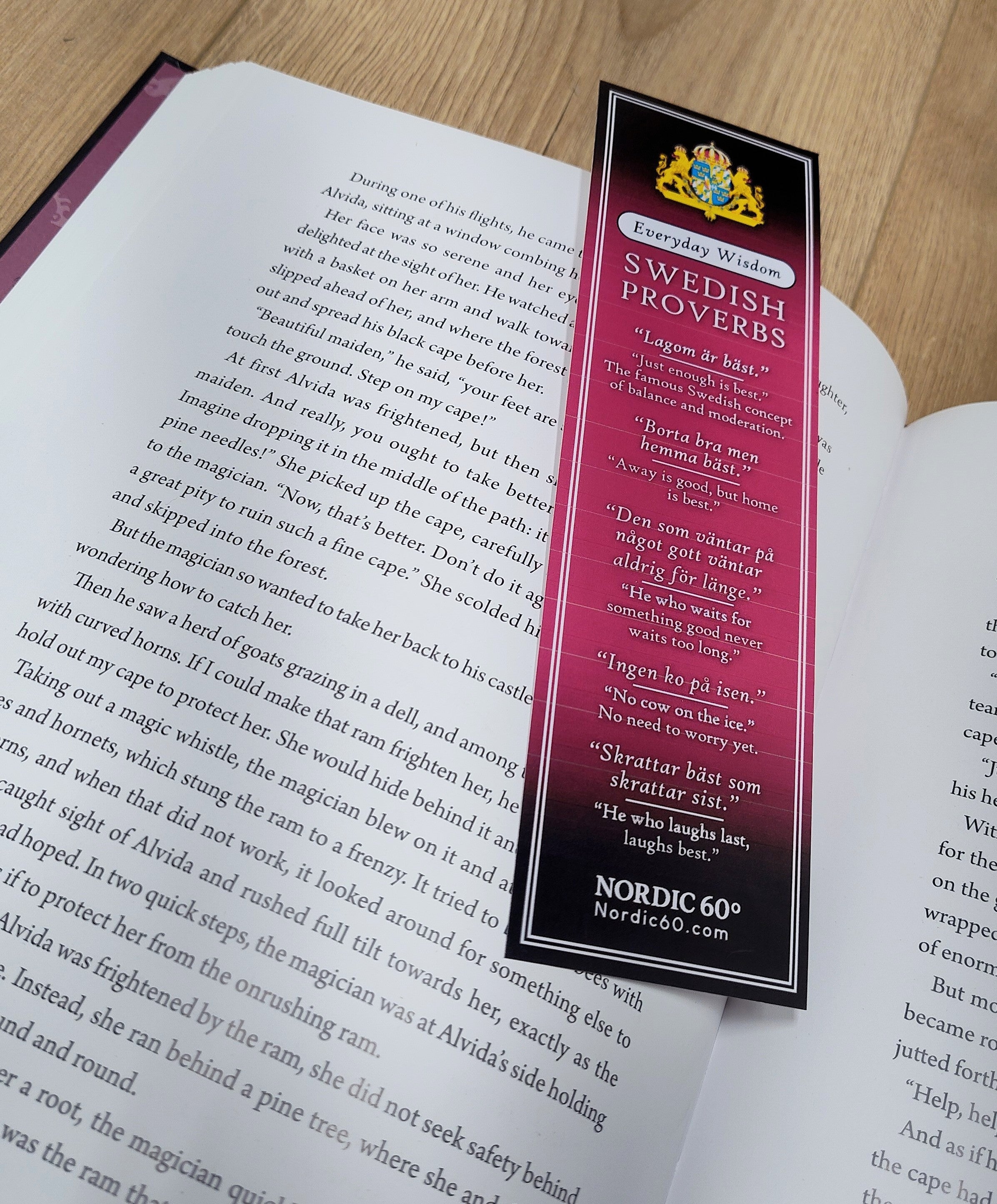 The Bookmark: Swedish Proverbs “Everyday Wisdom” (2.5" × 8.5") rests on an open book, displaying proverbs and translations, capturing Scandinavian tradition on a wooden surface.