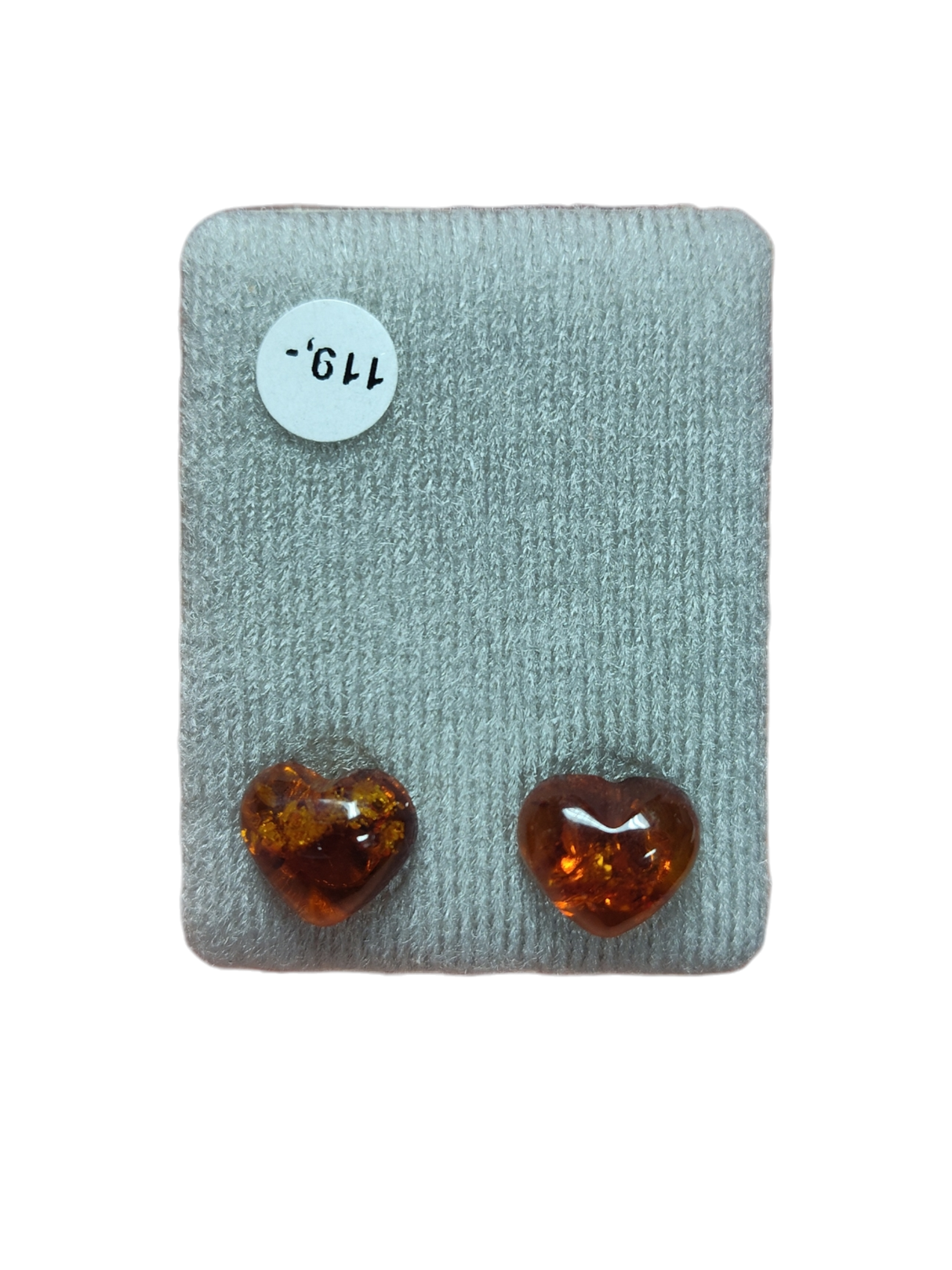 Two polished, heart-shaped amber stones rest on gray fabric beside a white "119" sticker, ideal for making Earrings: Heart-Shaped Amber Stud Earrings.