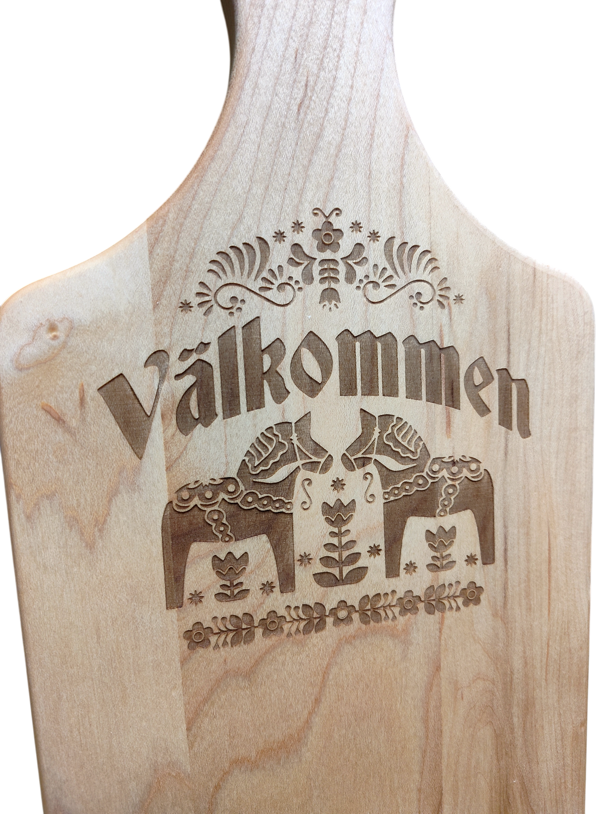 The "Valkommen" Maple Wood Cutting Board (13.5" x 7") features the Swedish word for welcome, two Dala horses, and detailed floral patterns inspired by Swedish folk art.