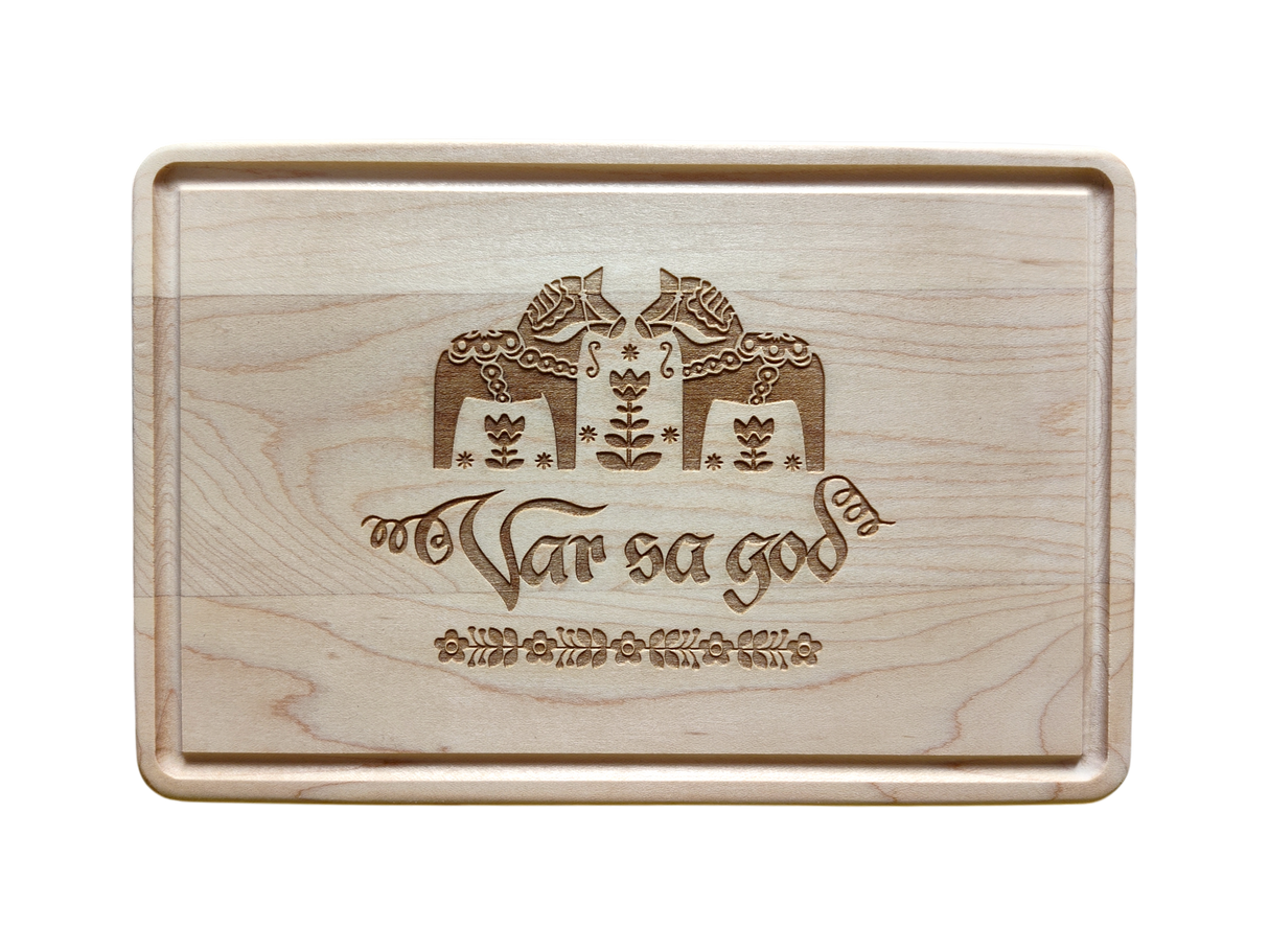 The Cutting Board: Var Sa God Maple Cutting Board (9"x6") features an engraved Scandinavian design and the phrase "Var så god" in script, making it a charming addition to any Scandinavian kitchen decor.