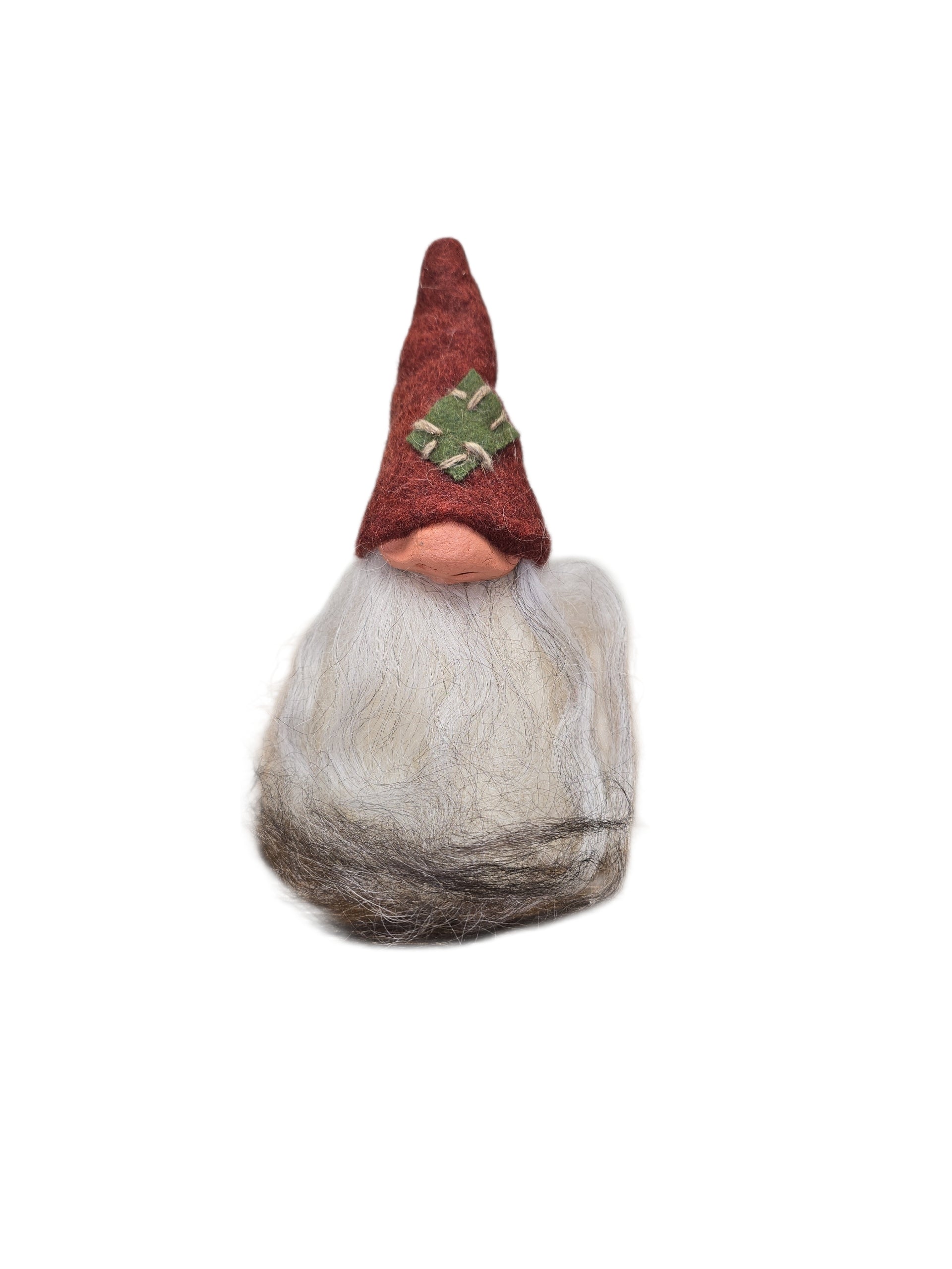 The "Patch Tomte" Gnome by Gumselids of Sweden is a 7" handcrafted figurine with a long gray beard, red pointed hat with green patch, on a wood base, inspired by Swedish tradition. Set against a white background.