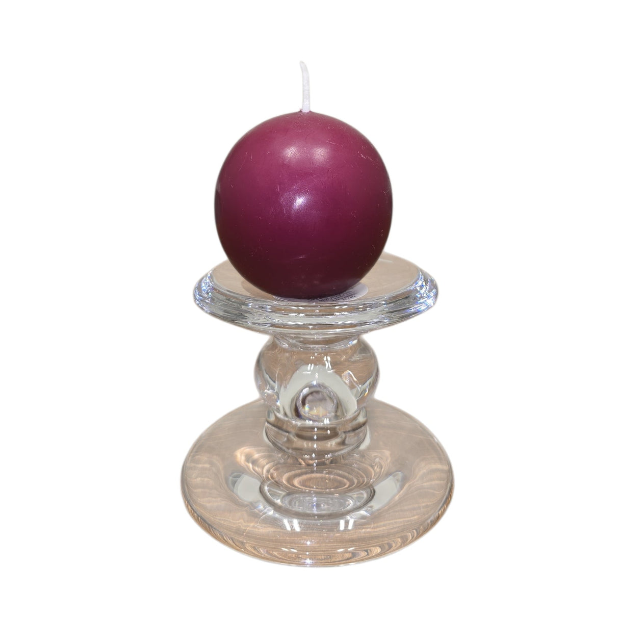 A Logum Kloster Lys 2.5" round dark purple ball candle from a 4-pack is displayed on a clear glass holder against a white background.