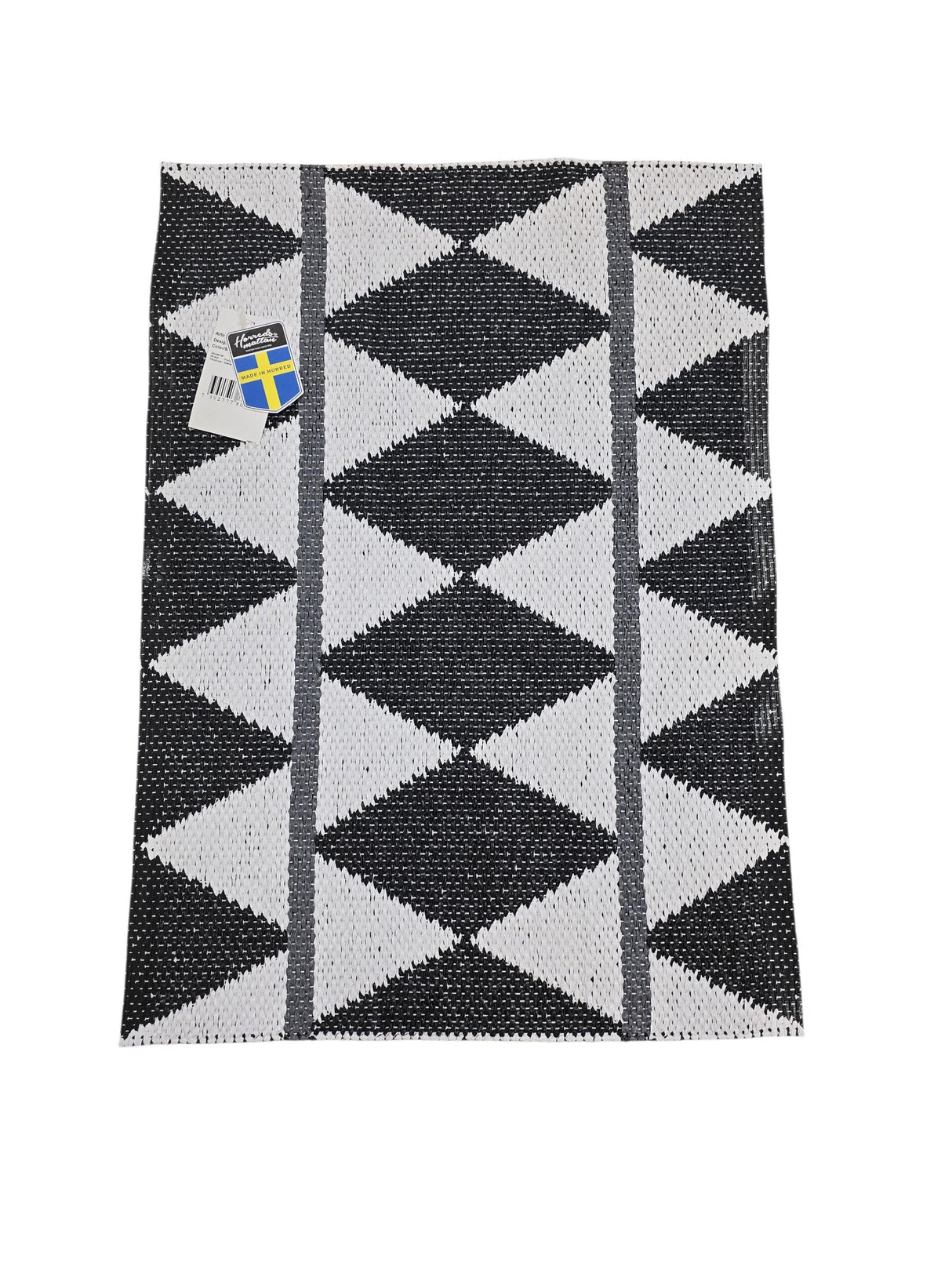 The Horredsmattan Zigge vinyl rug is rectangular and features a black and white geometric pattern with gray stripes on one side and a tag in the top left corner.