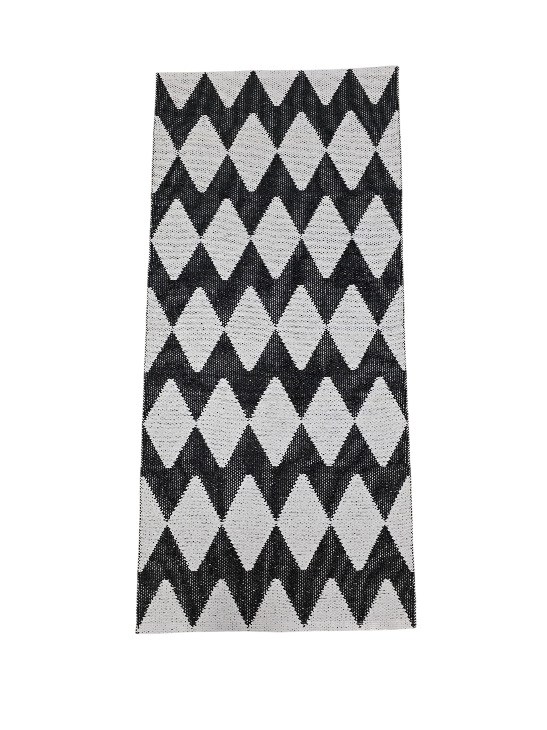The Vinyl Rug: Horredsmattan - Zigge features a rectangular shape with a black and white diamond pattern plus gray stripes on one side, shown against a white background.