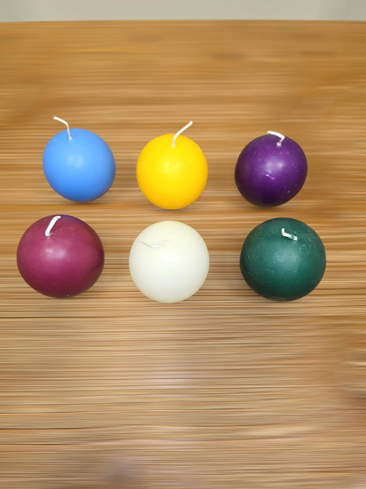 A 4-pack of Logum Kloster Lys 2.5" ball candles in assorted colors is arranged on a wooden surface, offering a stylish touch of Scandinavian décor to any room.