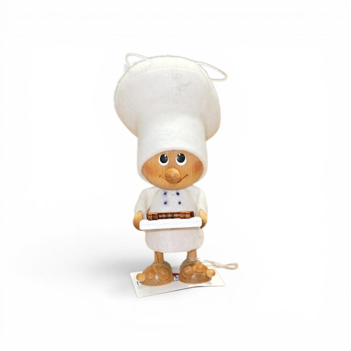 The Faire - Nordic Dreams Tomte Gnome Chef figurine is a 4.75" handcrafted Scandinavian ornament, featuring a chef with big eyes, a tall white hat, apron, and a tray holding a crab. It comes with an attached hanging string.