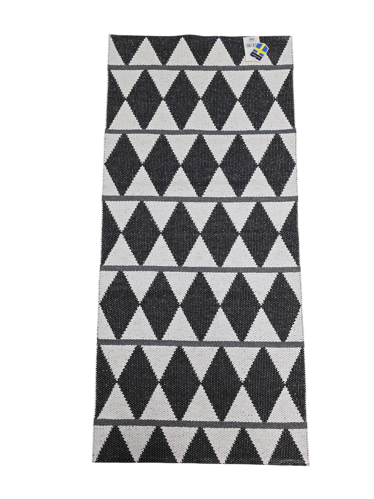 The Vinyl Rug: Horredsmattan - Zigge features a rectangular woven design with a black and white geometric diamond pattern, gray stripes on one side, and a small corner tag.