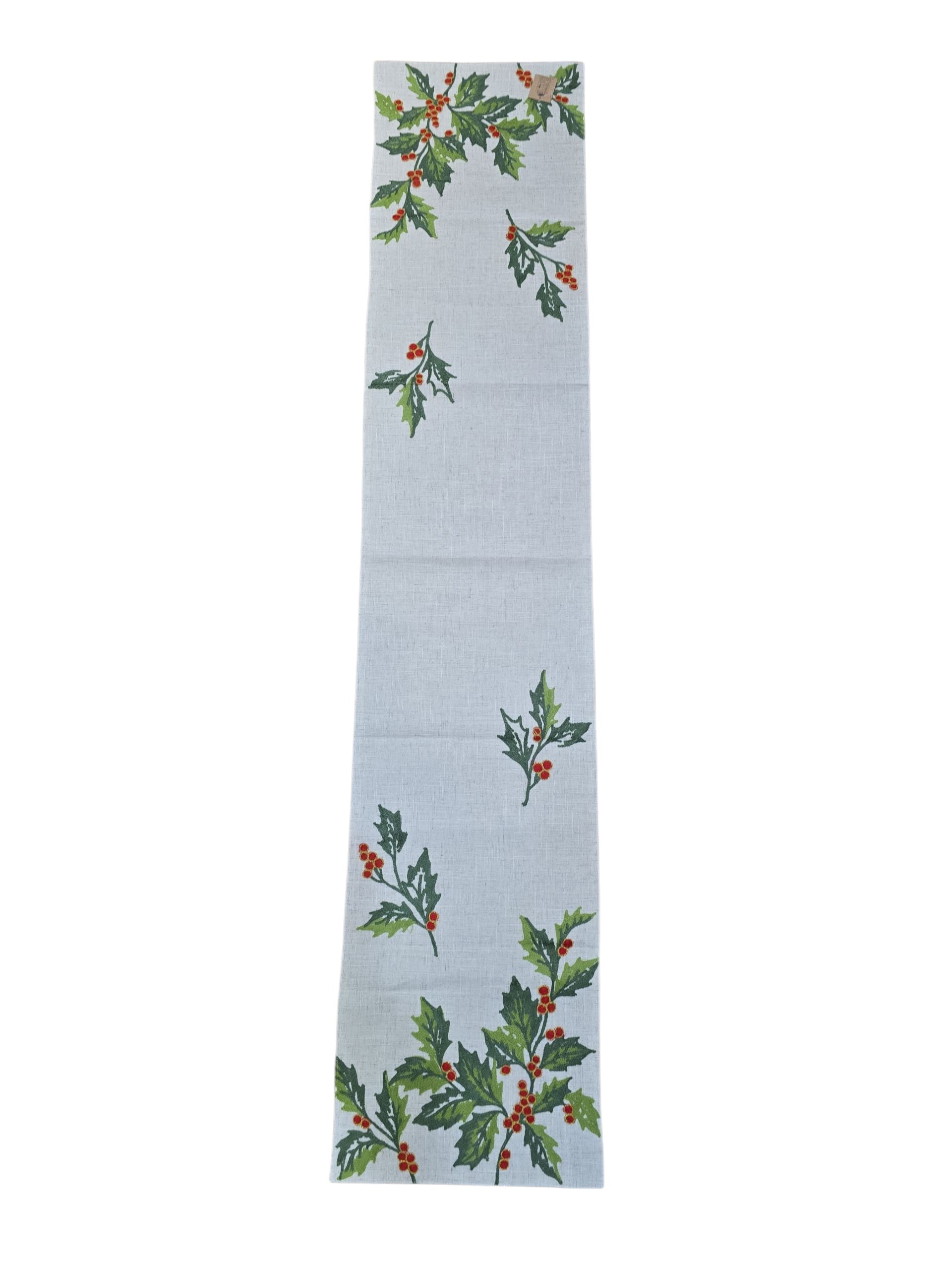 The Happy Holly Table Runner is a rectangular holiday runner with a white background and printed holly designs—green leaves and red berries—at both ends and in the center, perfect for festive Christmas decor.