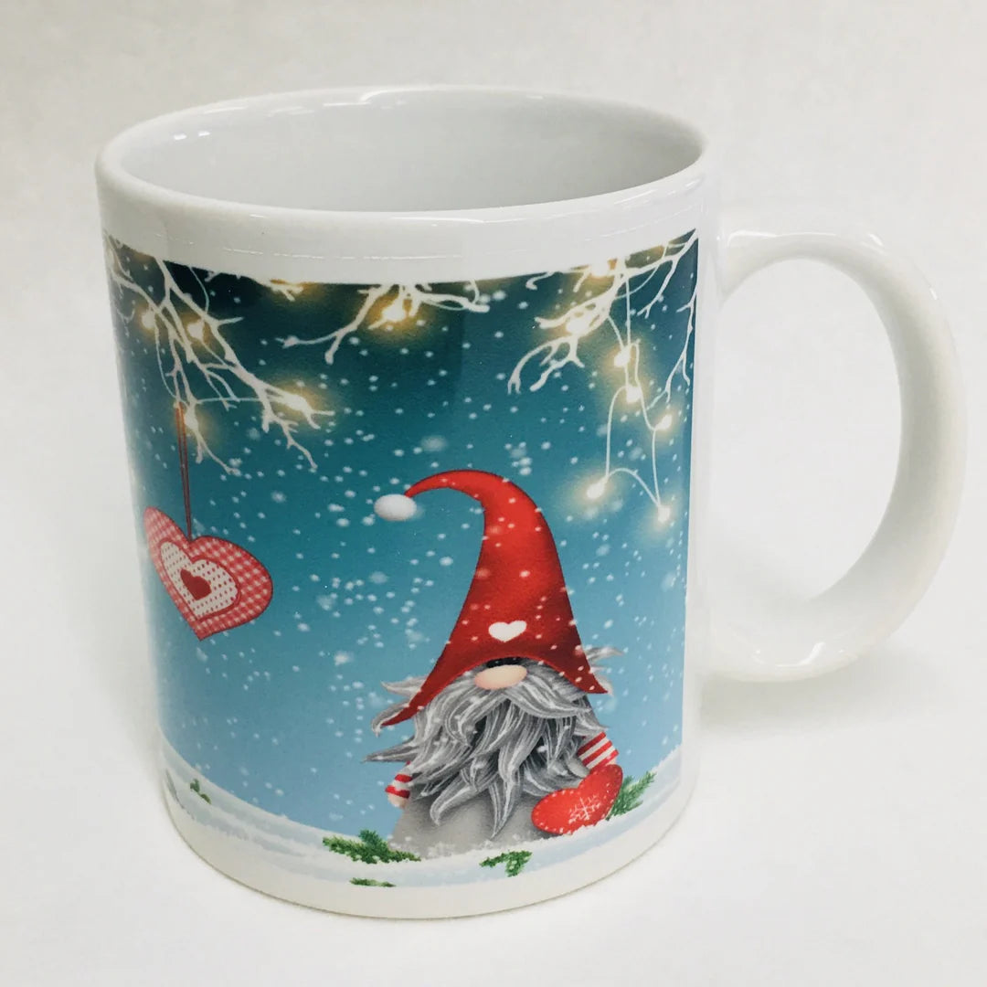 The Mug: Gnome with lights coffee mug features a cheerful gnome in a red hat, festive string lights, and falling snow on a blue background—ideal for cozy holiday mornings.