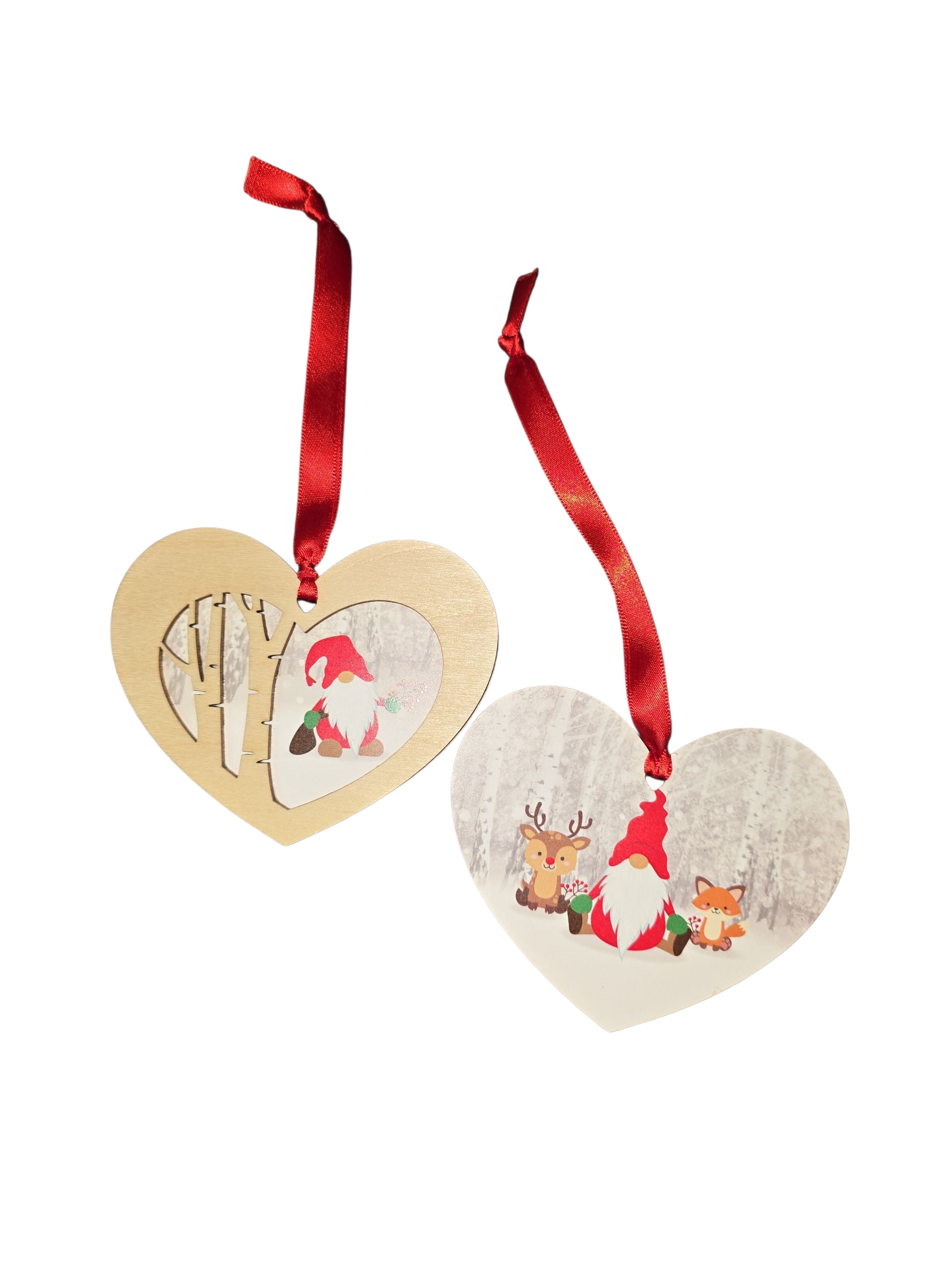 The Ornament: Tomte & Friends Heart Shaped Laser Cut Wood Ornament set includes two laser-cut wood hearts with red ribbons—one with a gnome, deer, and fox; the other features a forest scene and Tomte. A charming, unique Christmas tree decoration.