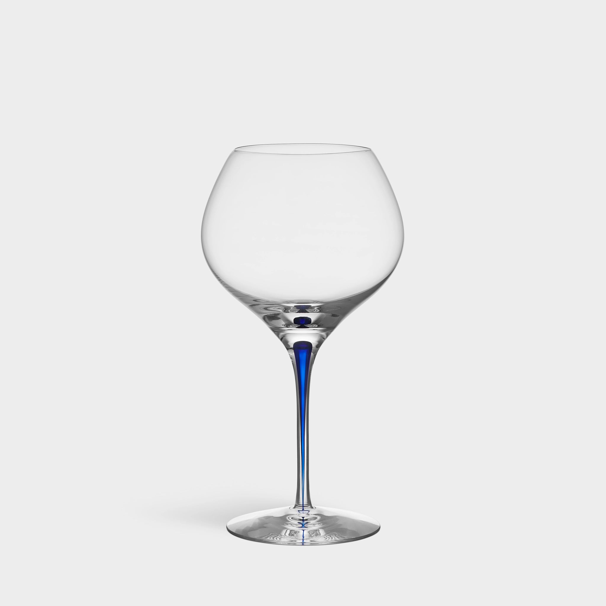 The Orrefors Intermezzo Blue Bouquet Glass 20oz, designed by Erika Lagerbielke, features clear glass with a rounded bowl and a slender blue stem, shown upright against a plain white background.