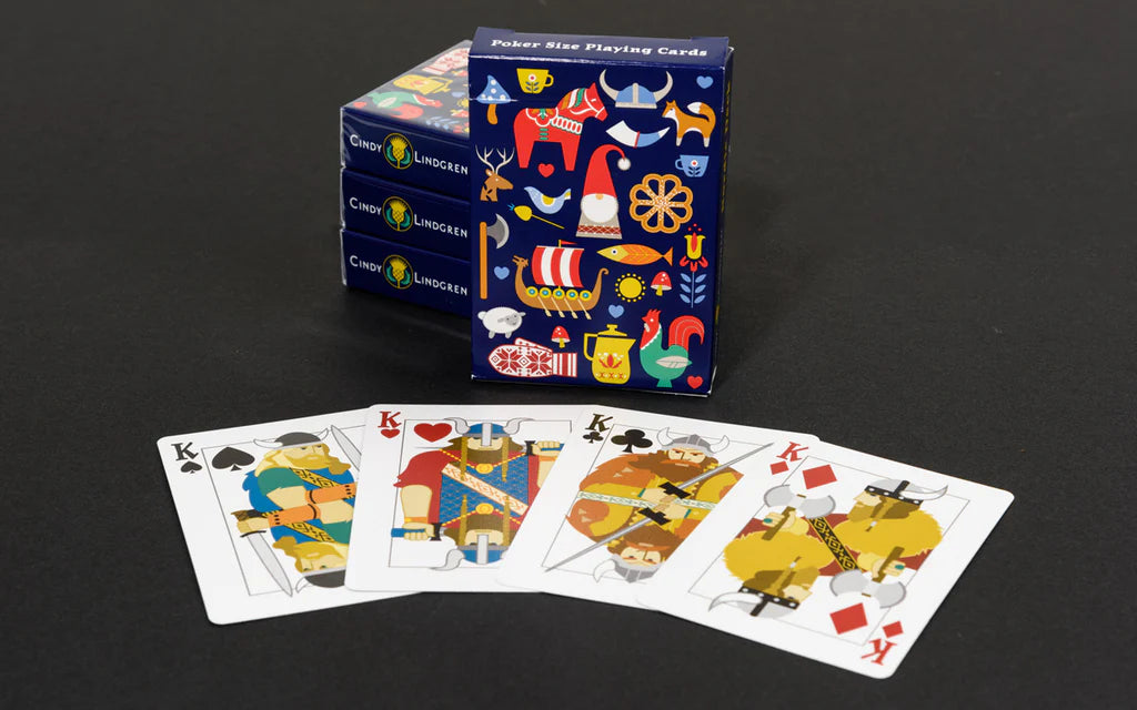 Four king cards are laid out in front of a box of the Playing Cards: Nordic Deck - Poker Size Playing Cards, which features colorful abstract graphics inspired by Nordic designs. Two more boxes appear partly visible in the background.