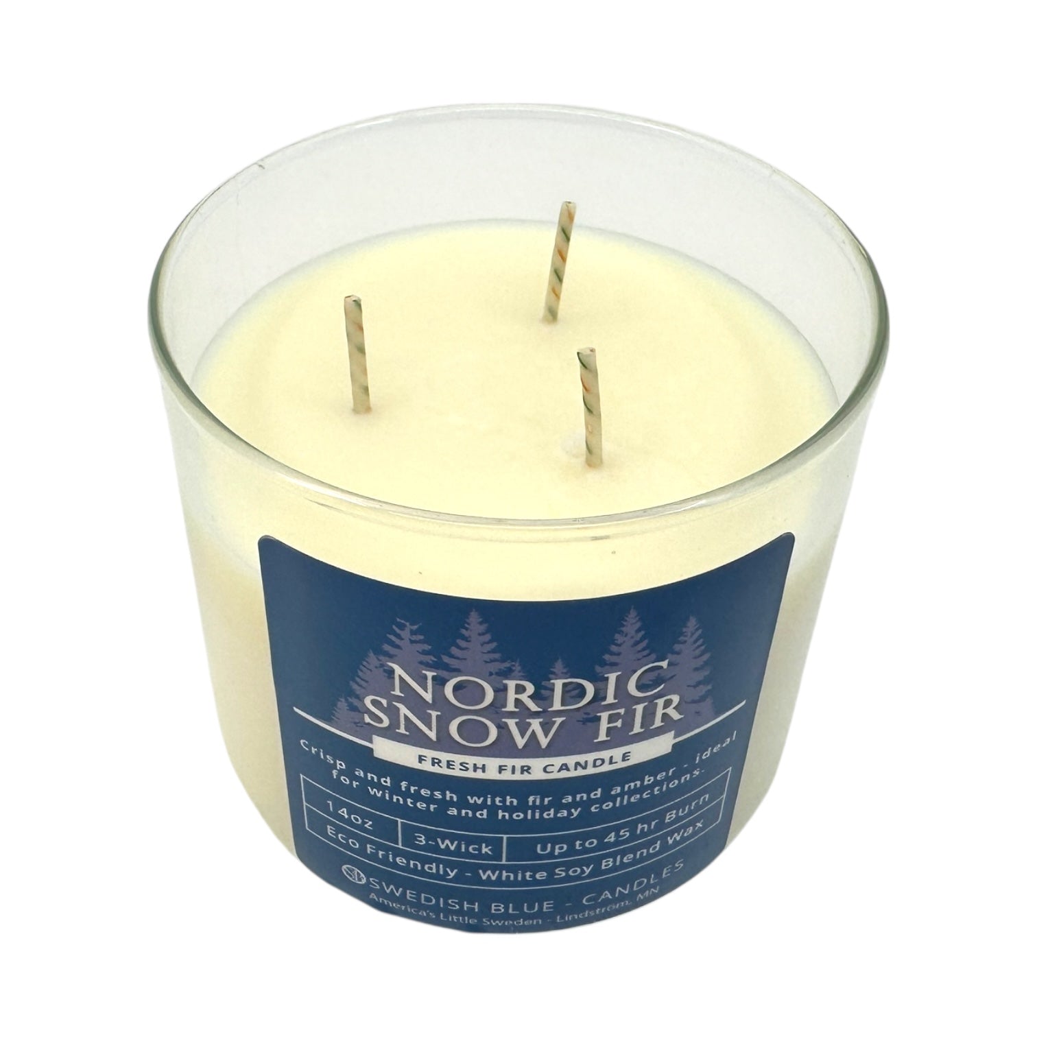 The Candle: Nordic Snow Fir – Fresh Fir Candle is a 14 oz, 3-wick white soy blend in a clear glass jar with a blue label featuring white text, tree graphics, and an inviting evergreen fir scent.