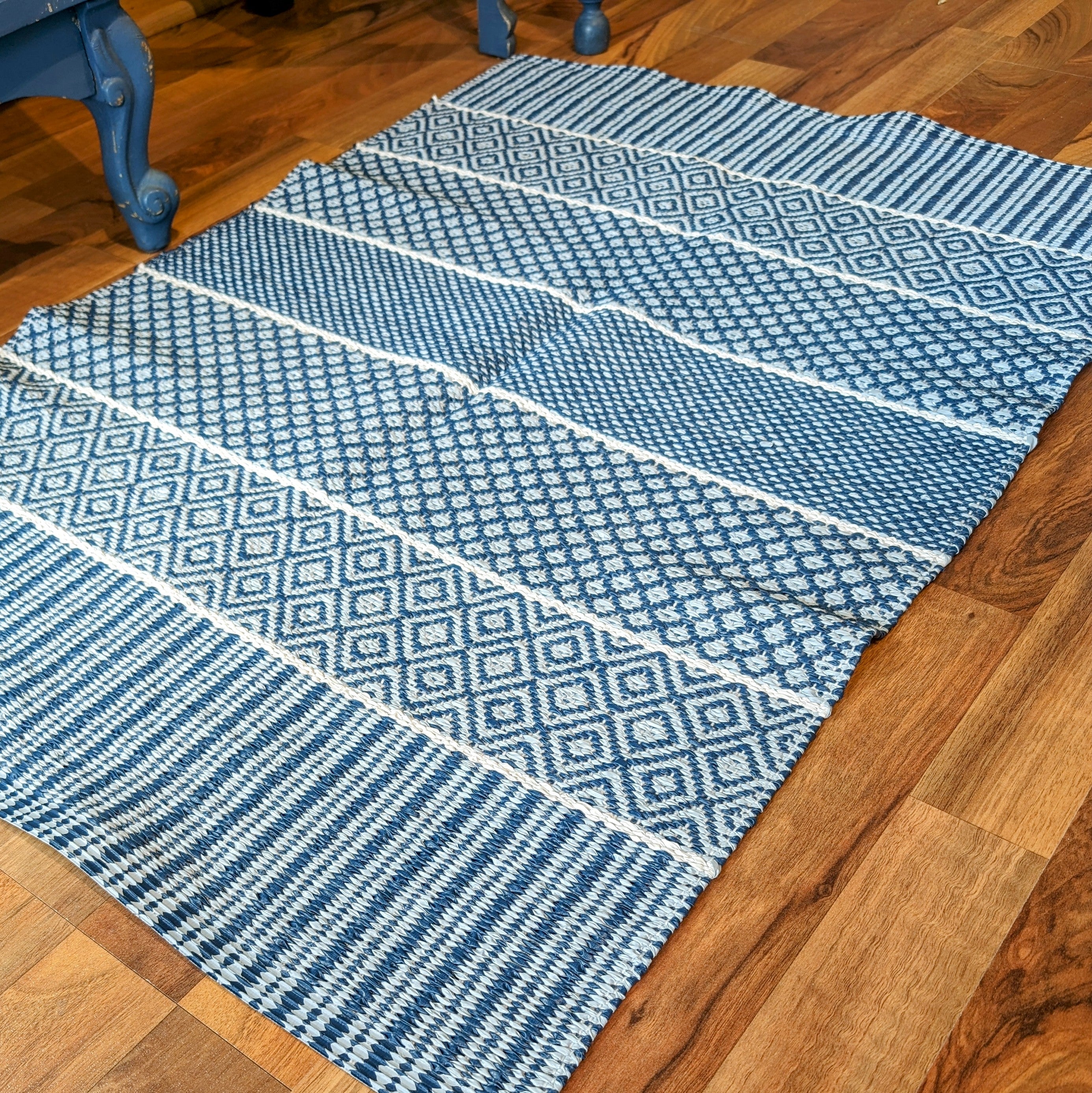 A Vinyl Rug: Horredsmattan - Alfie - Blue, featuring geometric patterns in blue and white, adorns the wooden floor.