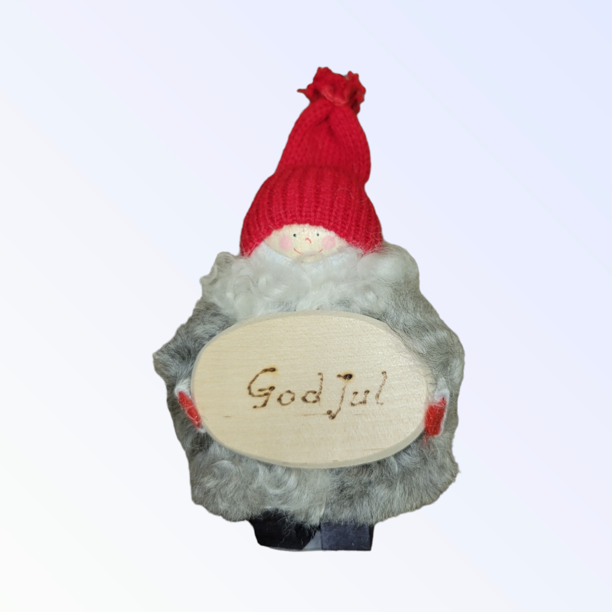 The Tomte with God Jul Sign figurine features a small gnome adorned with a red knit cap and a fluffy gray body, holding a wooden sign inscribed with "God Jul," meticulously handcrafted in Sweden.