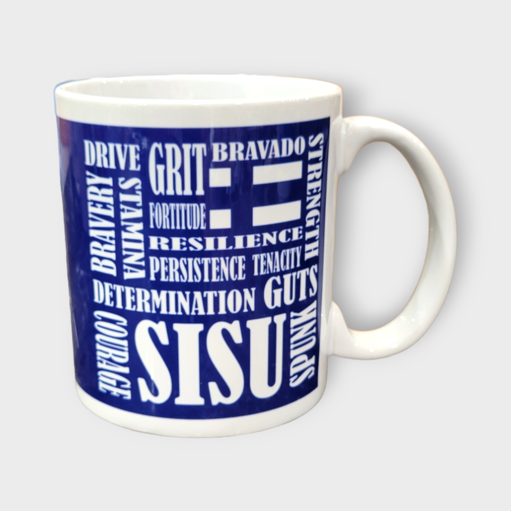The Coffee Mug: SISU Scramble (11oz) features a blue background and bold white text with motivational words like GRIT, BRAVERY, STRENGTH, and COURAGE. This Finnish-inspired ceramic mug inspires you with every sip.