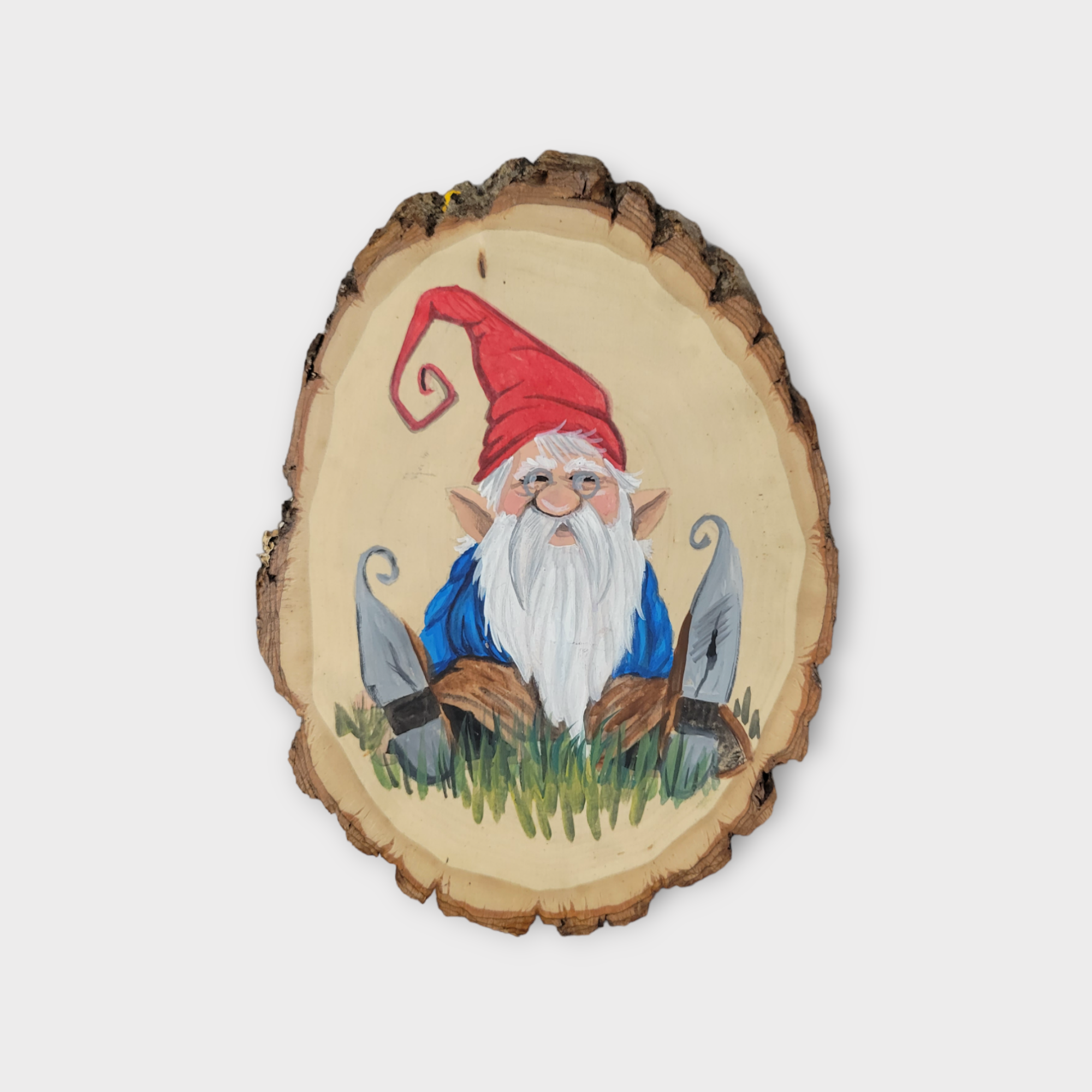 The "Artwork: Painted Gnome on Wood" by Pam Anderson features a gnome with a red hat and white beard sitting on a raw-edged wooden plaque, surrounded by grass and grey mushrooms.