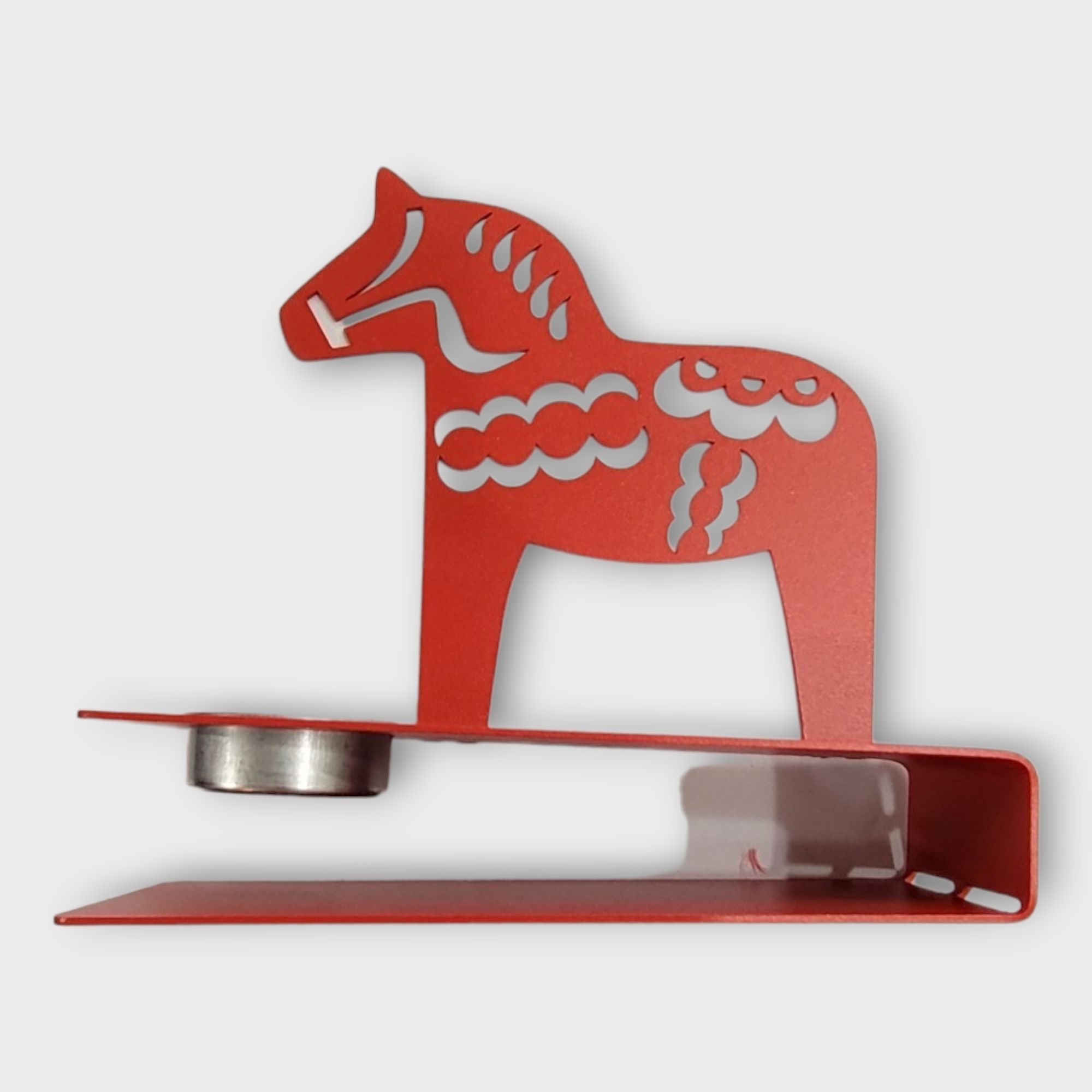 A metal tea light candle holder designed in the shape of a stylized red Dala Horse captures Scandinavian charm, making it an excellent choice for infusing Swedish décor into any space.