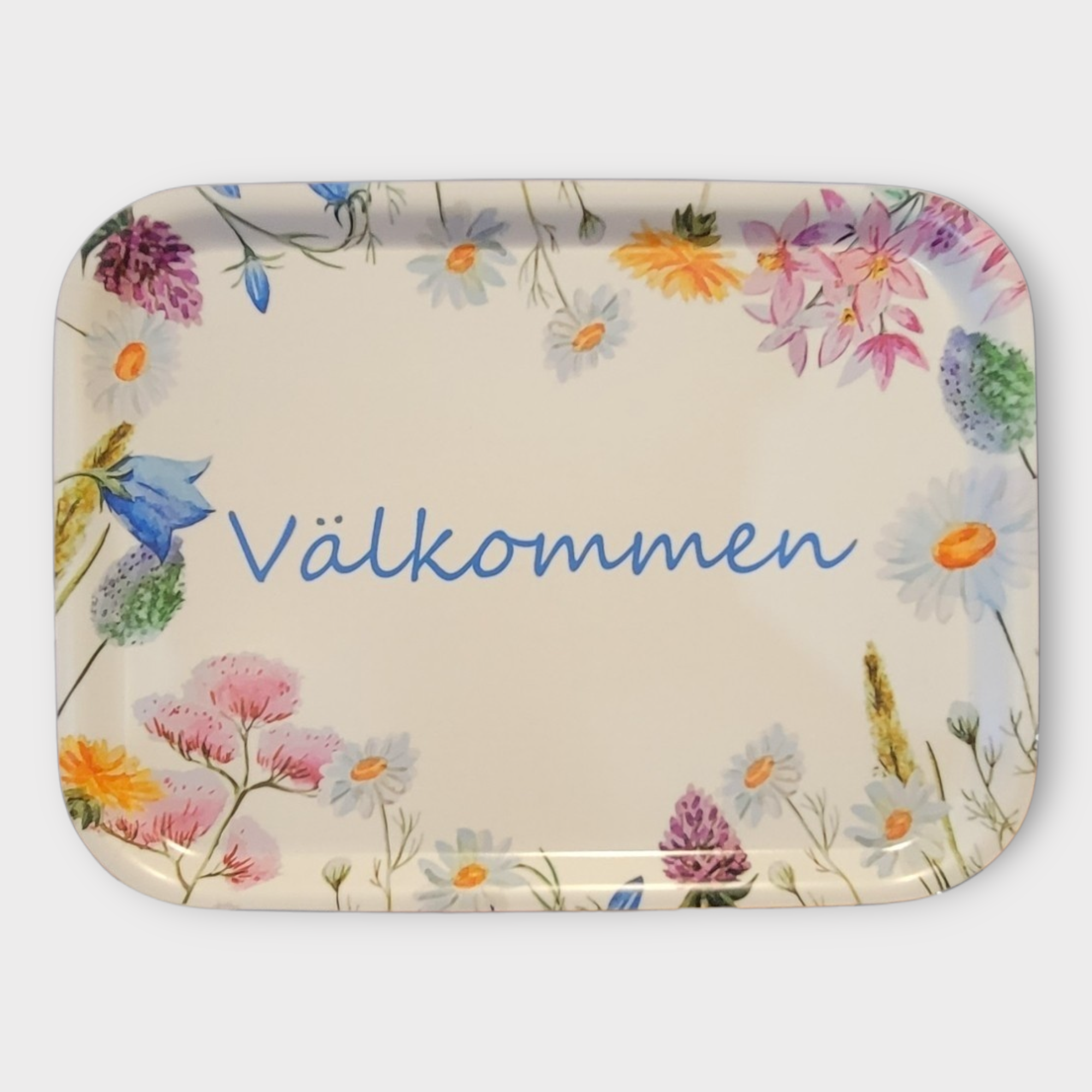 The Tray: Valkommen 27x20cm is a handcrafted rectangular tray, adorned with a vibrant floral border and the word "Välkommen" in blue text at the center, capturing Nordic charm through its Scandinavian design.