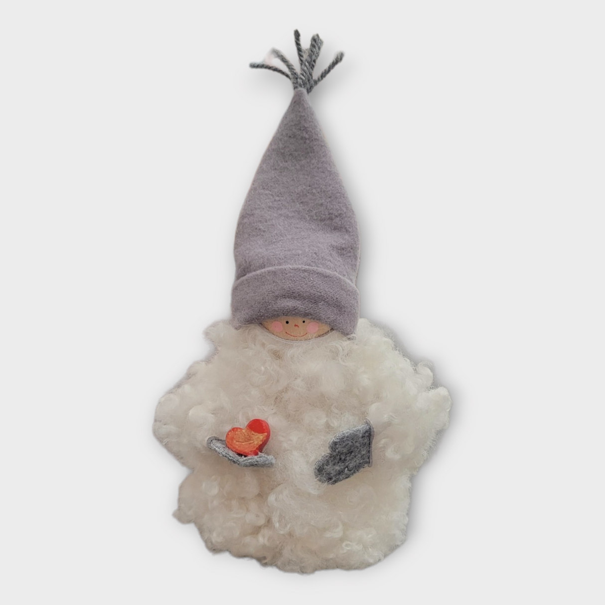 The Figurine: Sheepskin Tomte "Gnome" Holding a Heart features a small Scandinavian gnome with a fluffy beard, gray hat, and red heart—ideal as Swedish table decor.