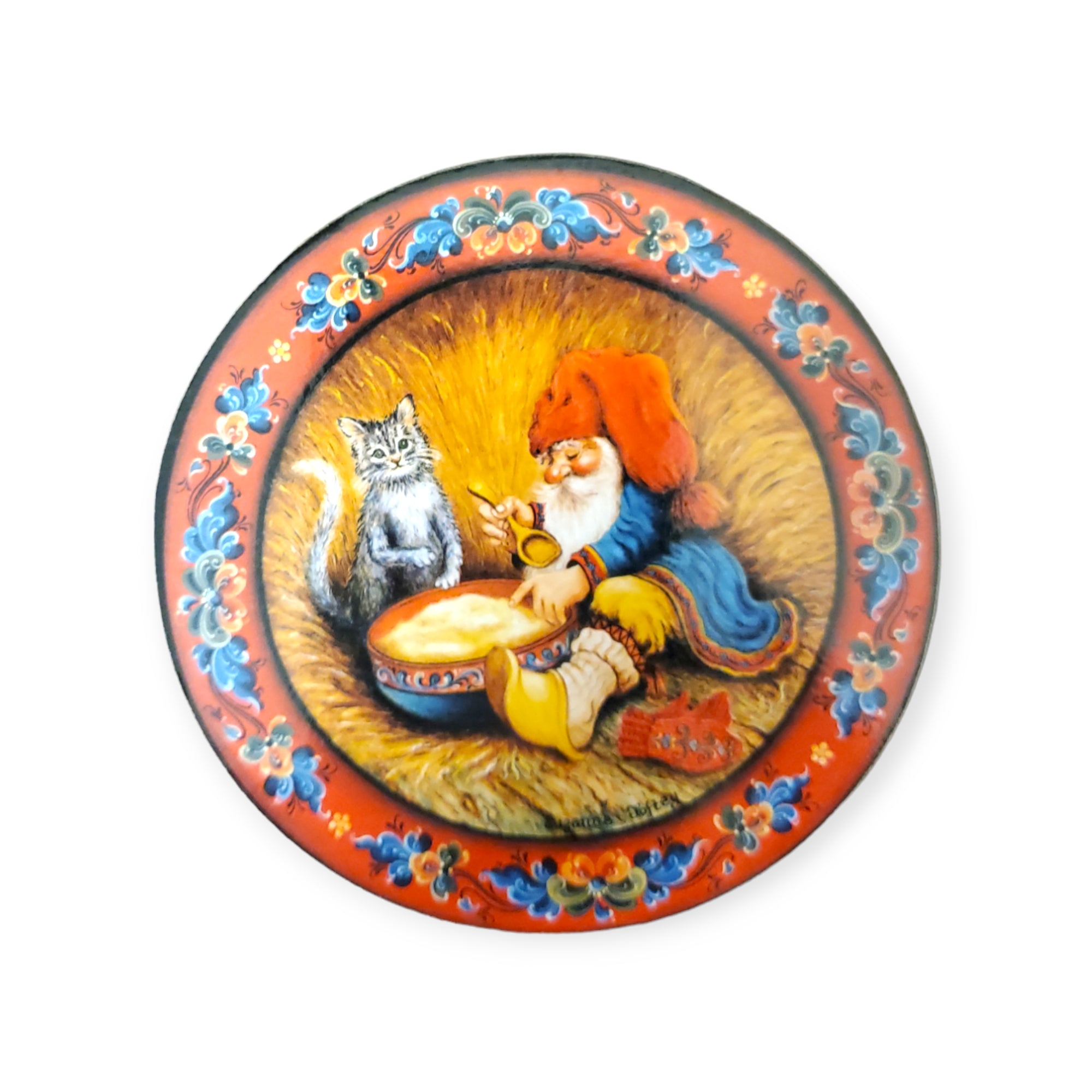 Glassbrikker 6 pack featuring a tomte in a red hat pouring tea, sitting beside a cat on a straw background. The border has blue and red floral patterns, adding julestemning to your home.